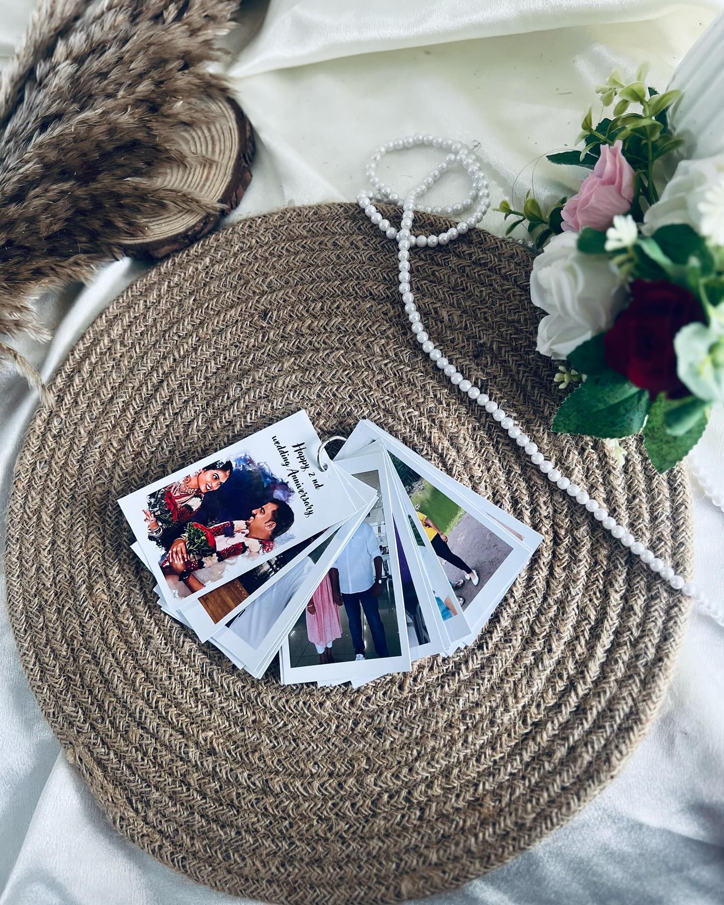 A fanned set of personalized wedding polaroid prints paired with pearls and roses for a romantic anniversary keepsake.