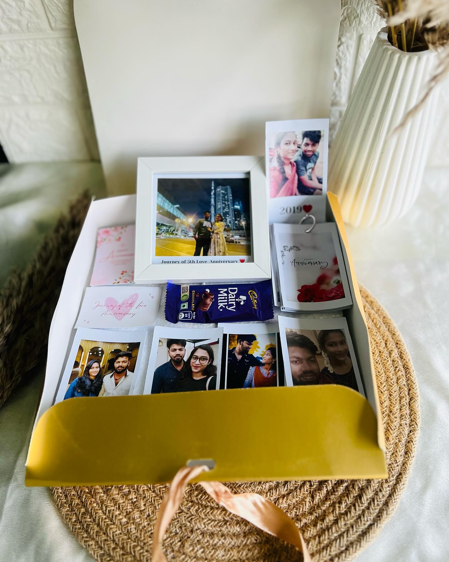 An elaborate anniversary keepsake box filled with a personalized photo frame, polaroid memories, chocolates, and greeting cards.
