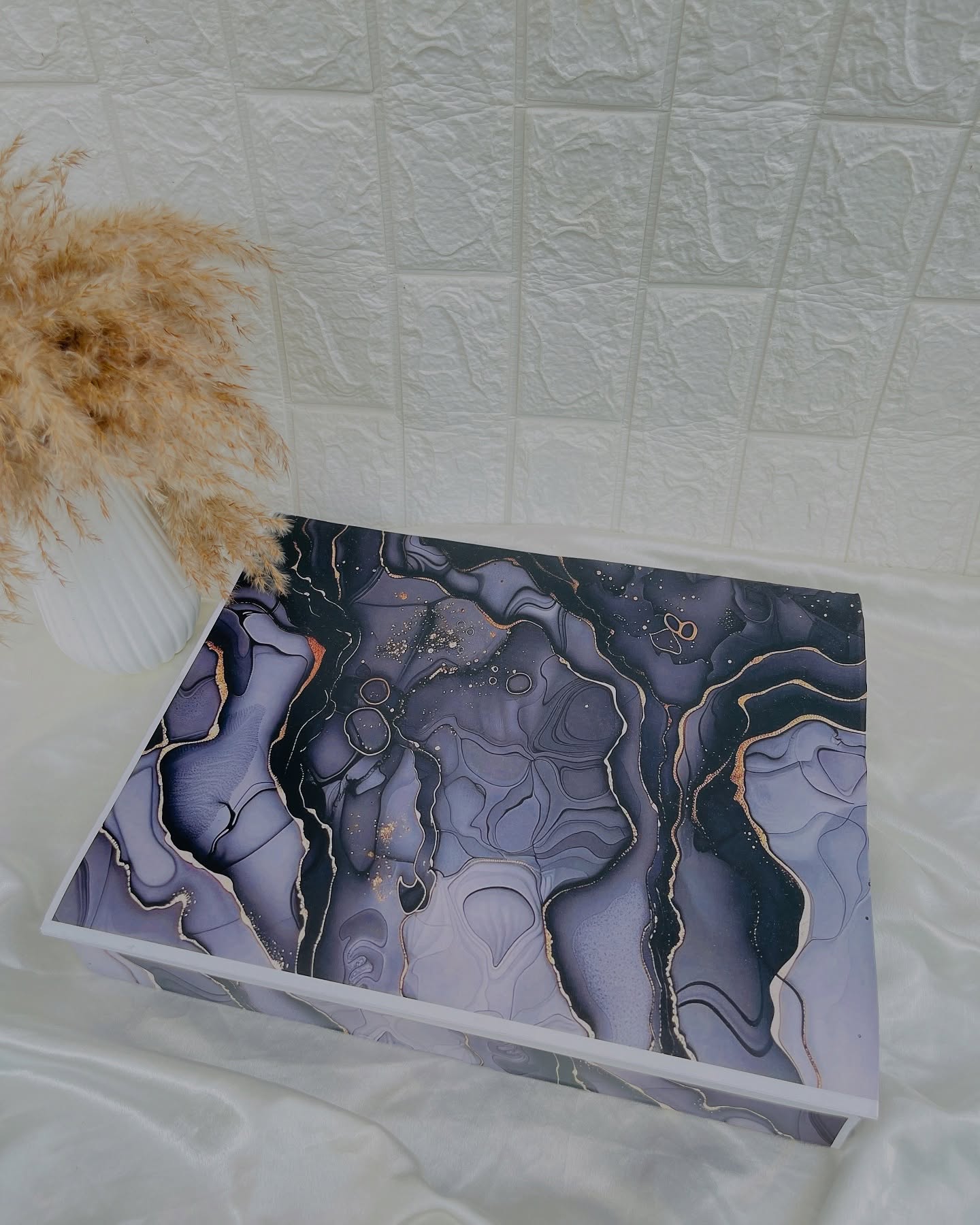 A sleek gift box wrapped in a deep purple and gold marble-effect design, ideal for an elegant surprise.