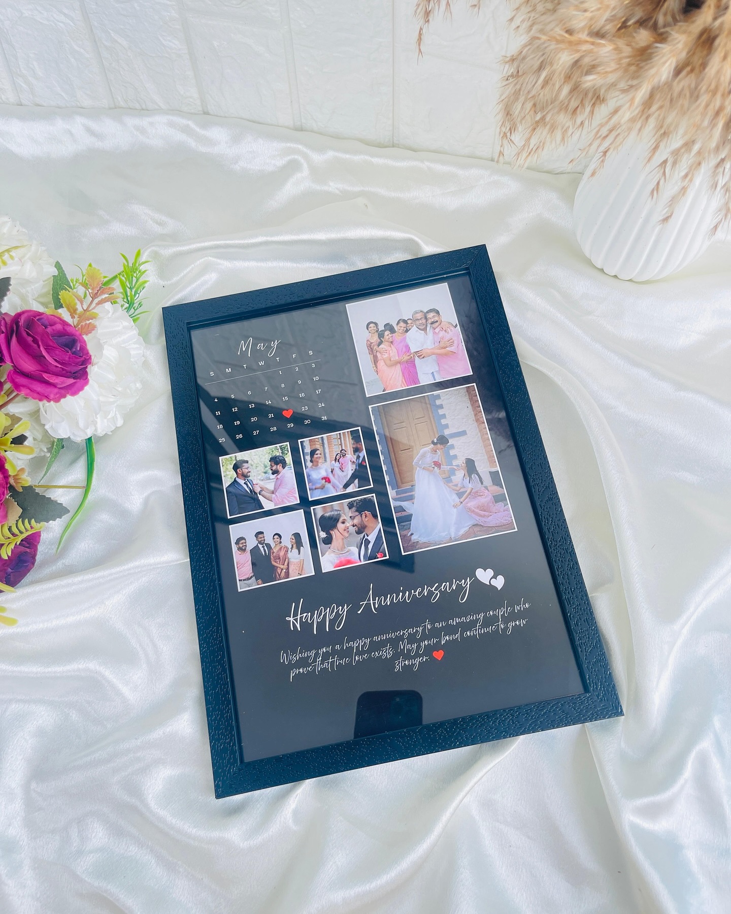 A framed photo collage with a monthly calendar and heartfelt anniversary message, built from the couple's own moments.