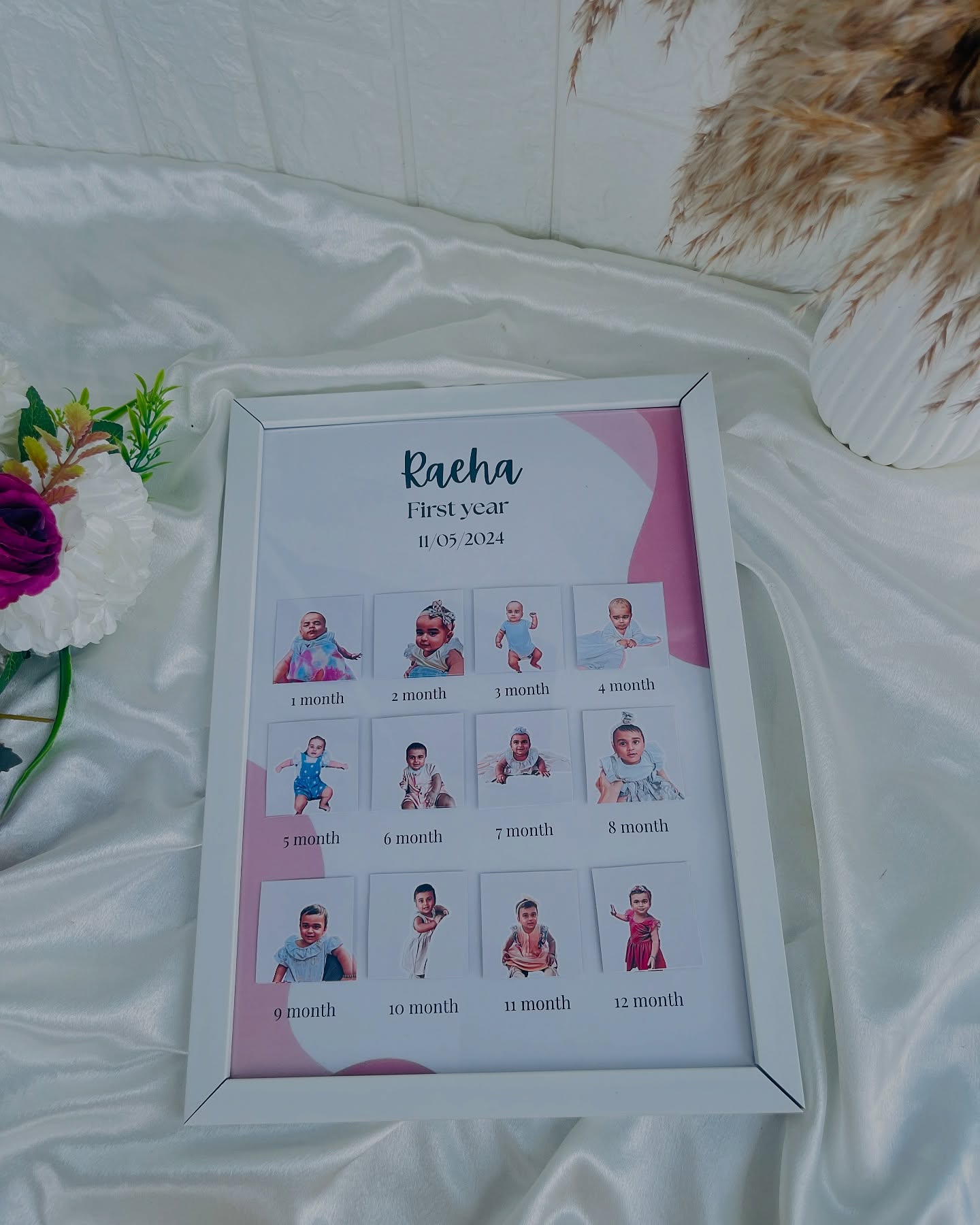 A framed month-by-month photo collage celebrating a baby's first year with name and birth date.