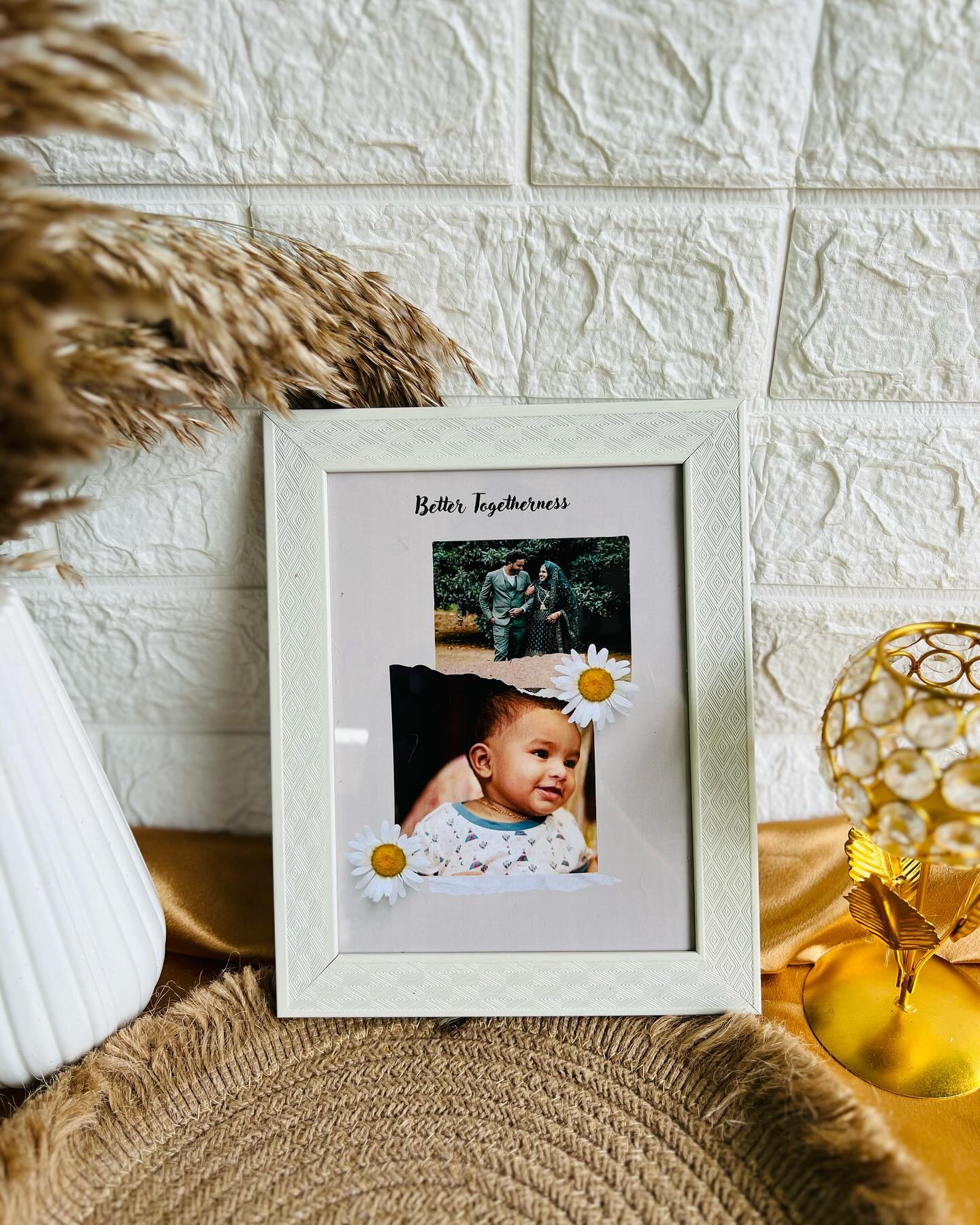 A daisy-trimmed photo frame pairing a couple portrait with a baby photo under the caption Better Togetherness.