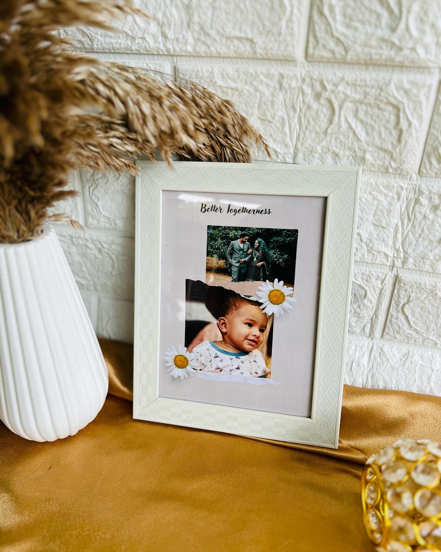A personalized keepsake frame pairing a couple's wedding portrait with a sweet baby photo, finished with dried daisies.