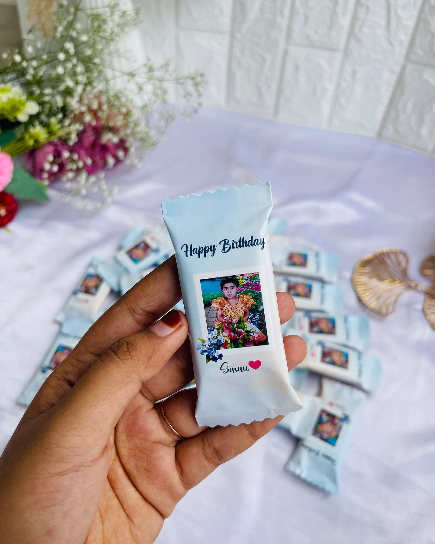 A set of personalized 'Happy Birthday' chocolate bars, each wrapped with the same cherished childhood photo.