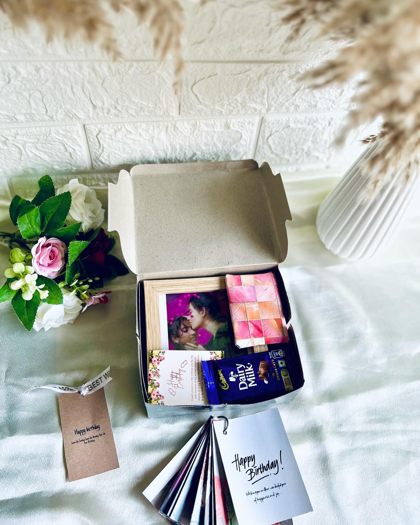 A birthday gift box with a couple's photo frame, a chocolate mosaic block, Cadbury Dairy Milk and a flip-book card.