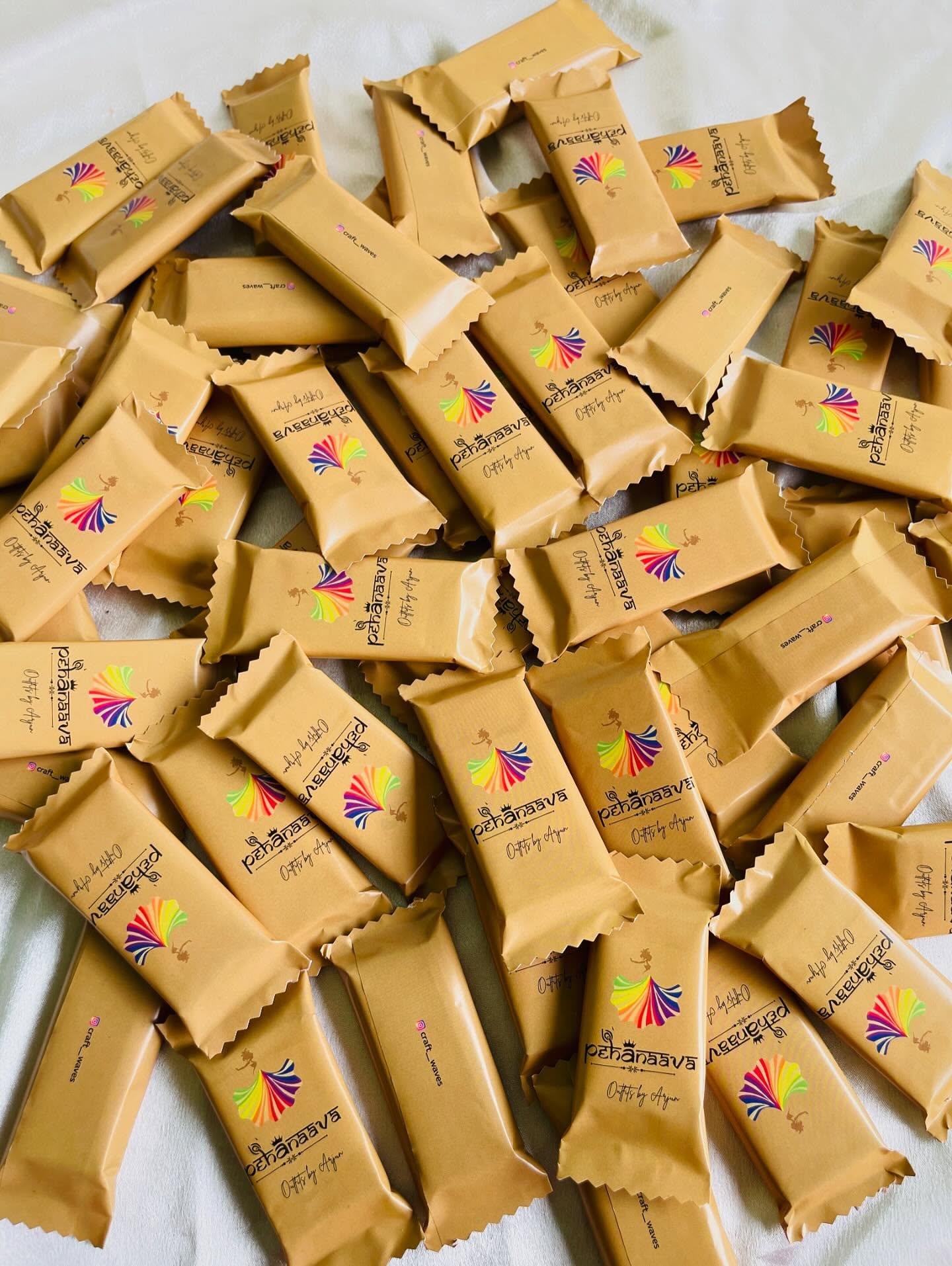 A bulk batch of gold-wrapped chocolate bars custom branded with a company logo for corporate giveaways.