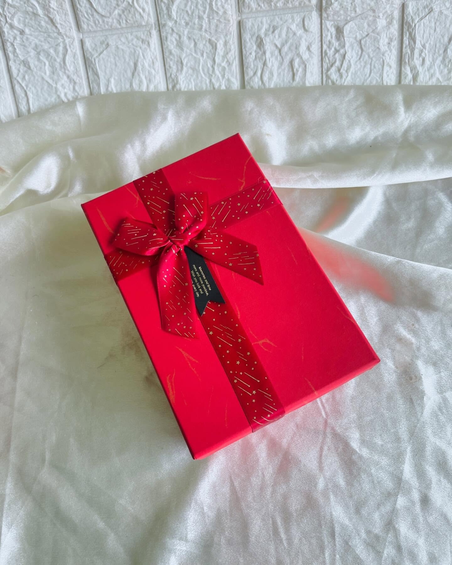 A ready-wrapped red gift box tied with a starry red satin bow and a heartfelt message tag.