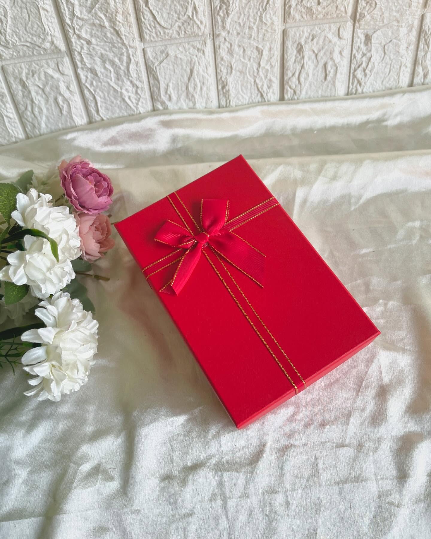 A statement red gift box finished with a satin-and-gold bow, ready to hold a curated surprise inside.