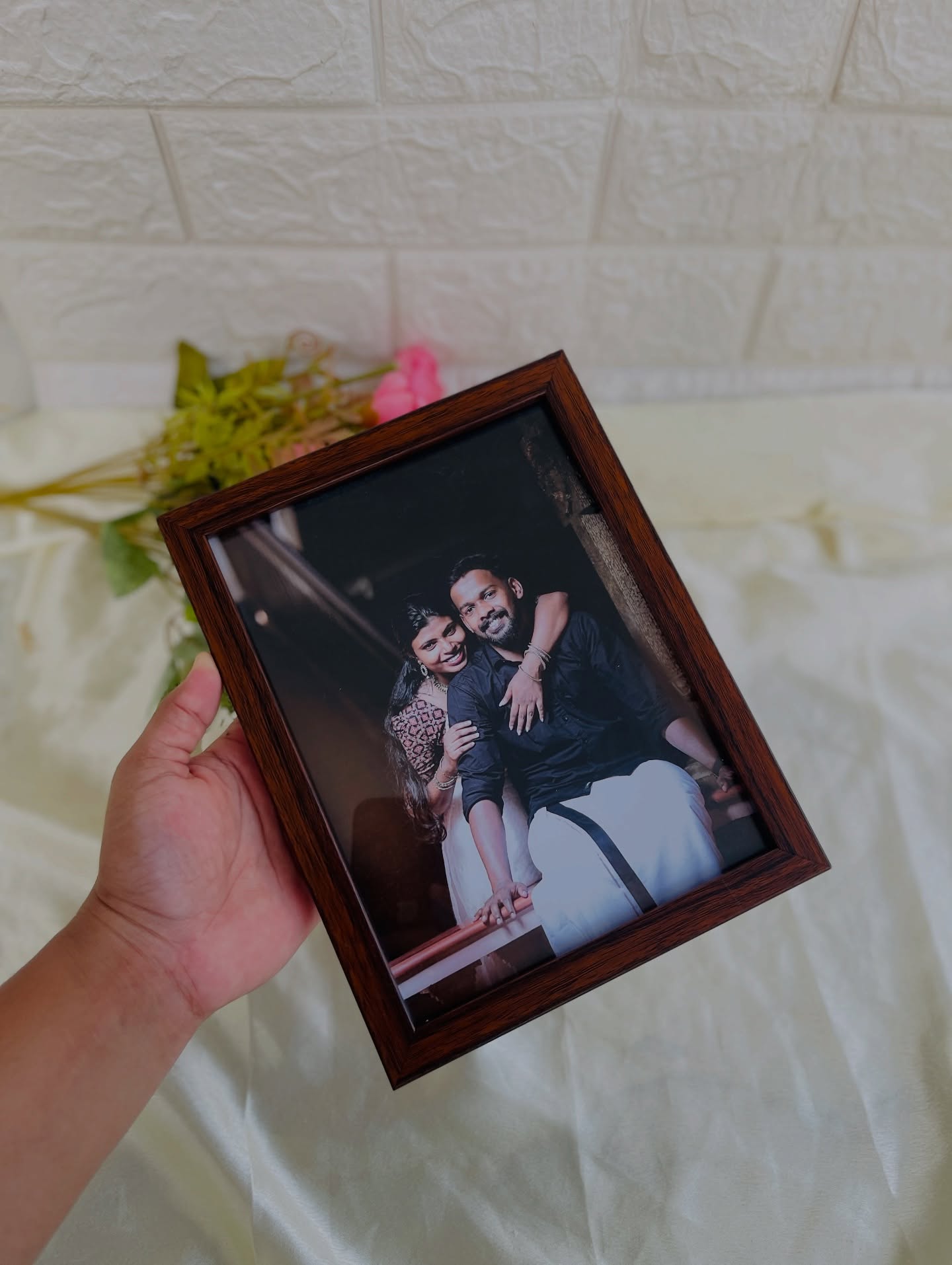 A dark wood-framed couple's portrait, styled with a single rose for a romantic keepsake.