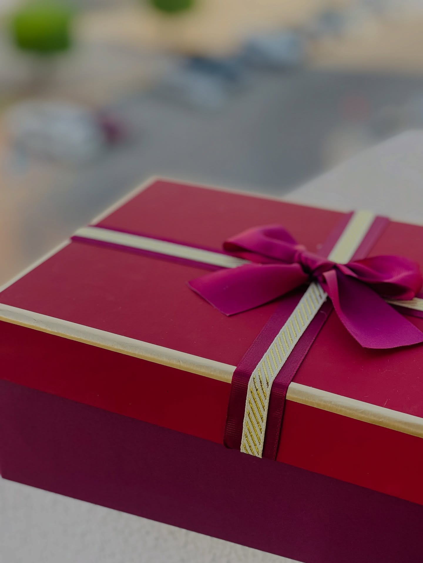 A rich crimson gift box wrapped in a magenta grosgrain ribbon and finished with a bold bow, ready for any celebration.