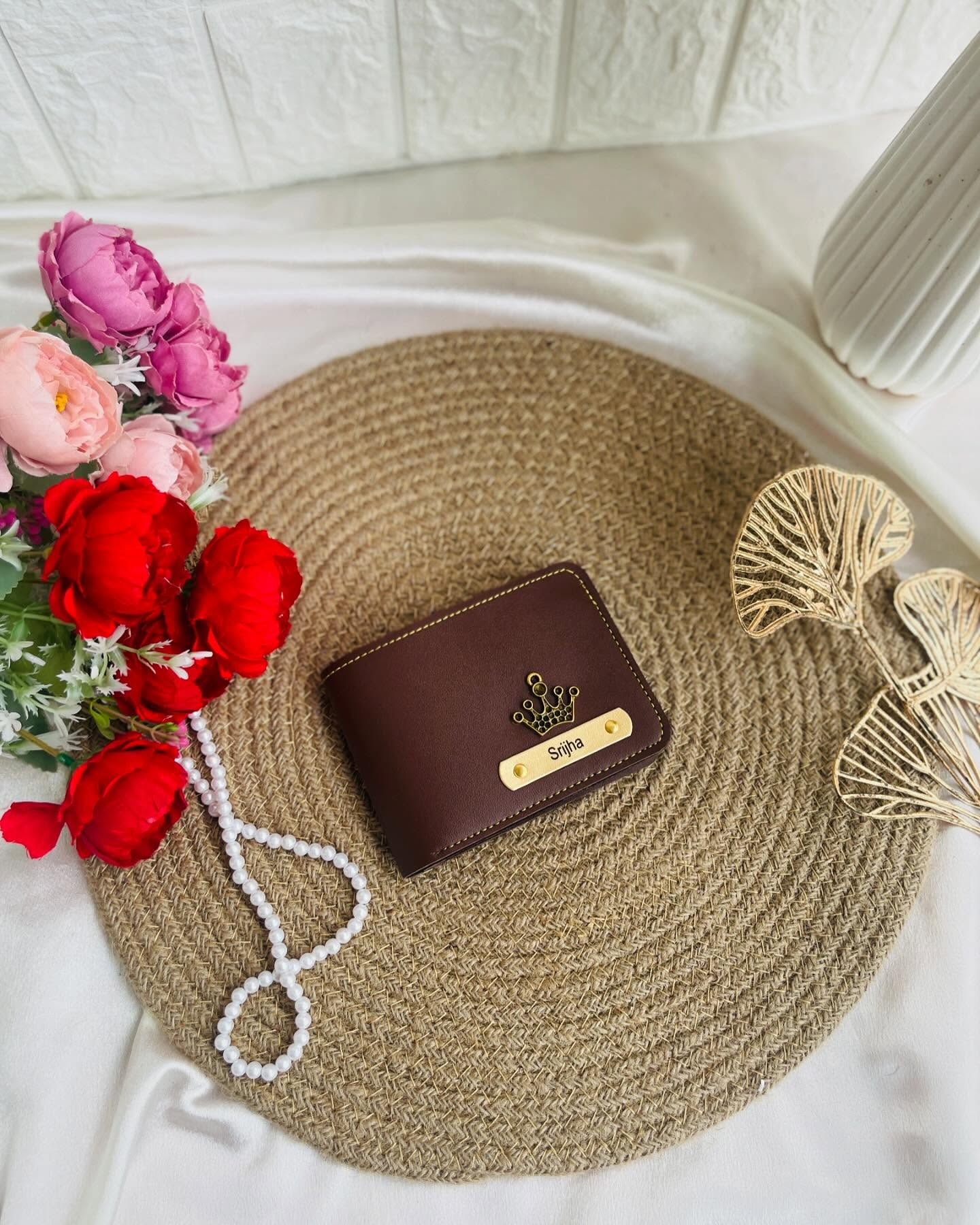 A rich brown leather wallet with a personalized crown nameplate and pearl accents.