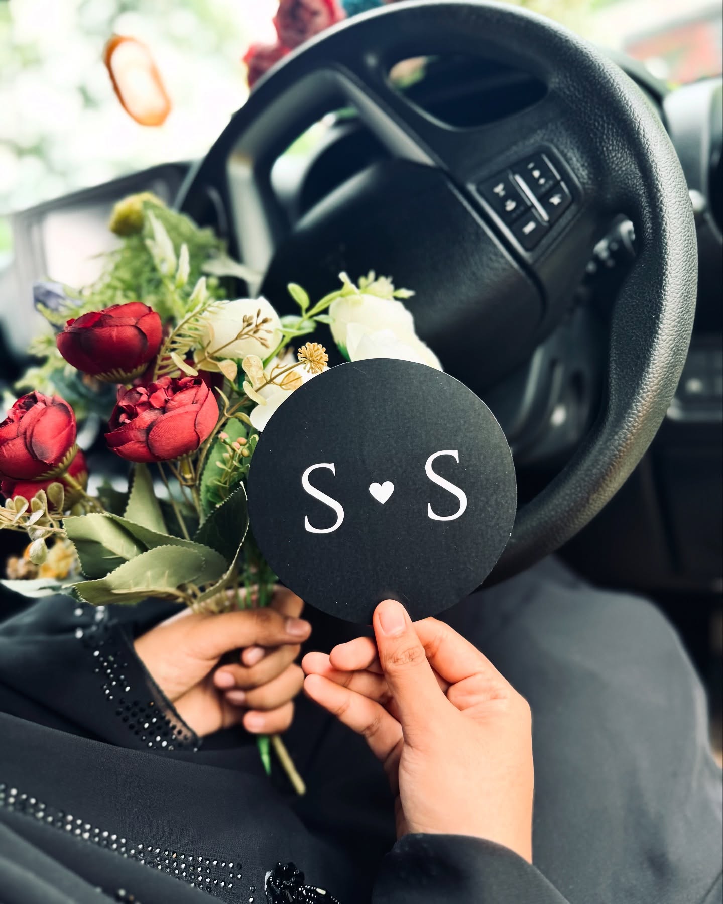 A personalized black acrylic couple name plaque paired with a lush mixed flower bouquet.