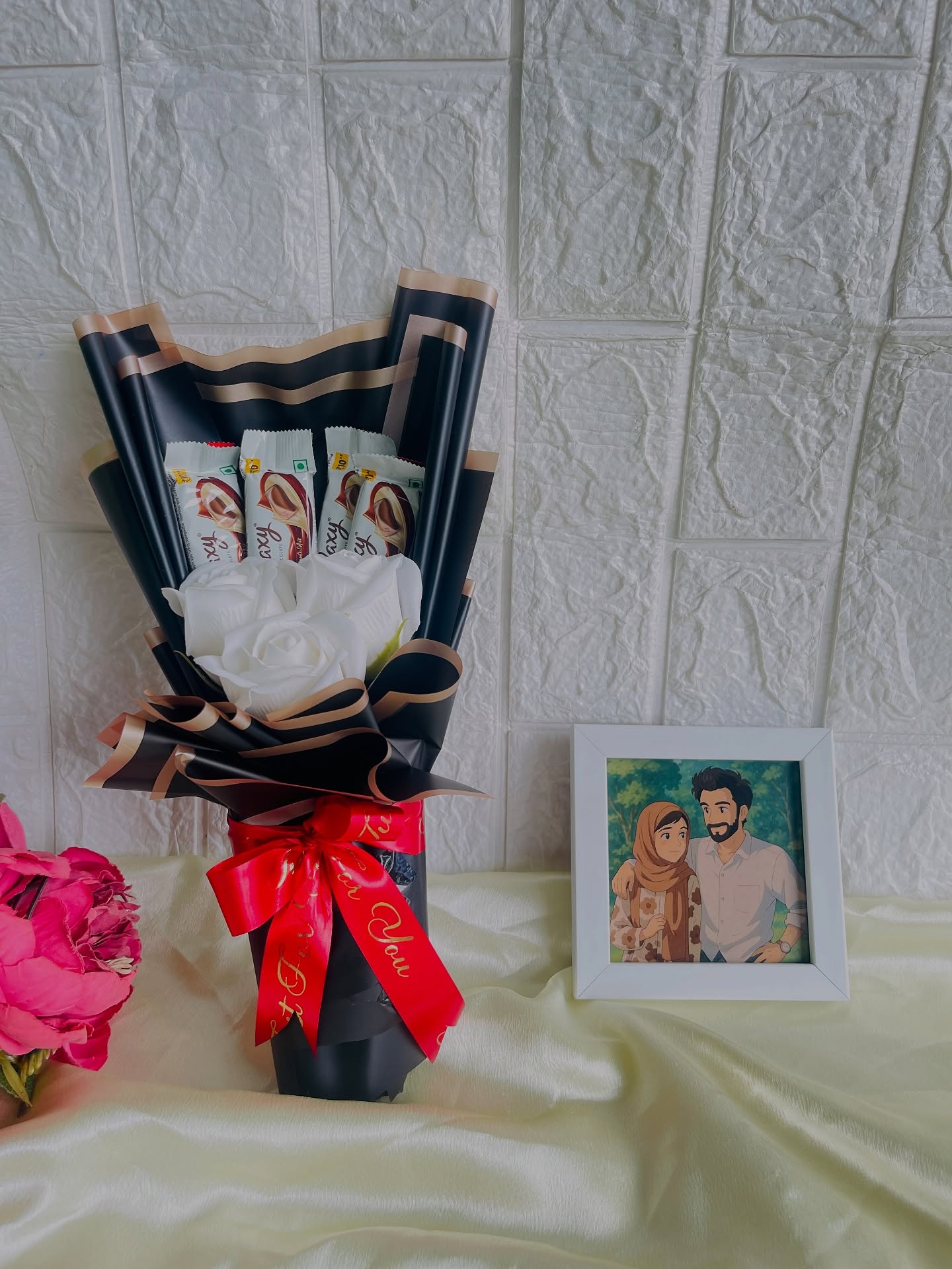 A chocolate and rose bouquet wrapped in black and gold, paired with a custom illustrated couple portrait.