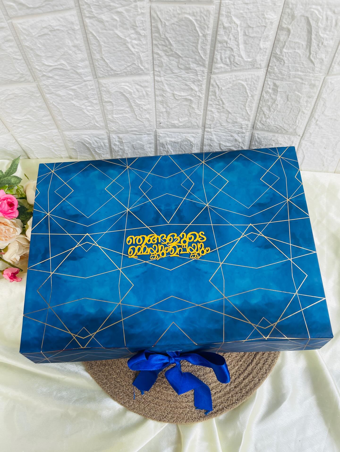 A striking navy gift box with gold geometric foiling and a custom printed message, tied with a satin bow.