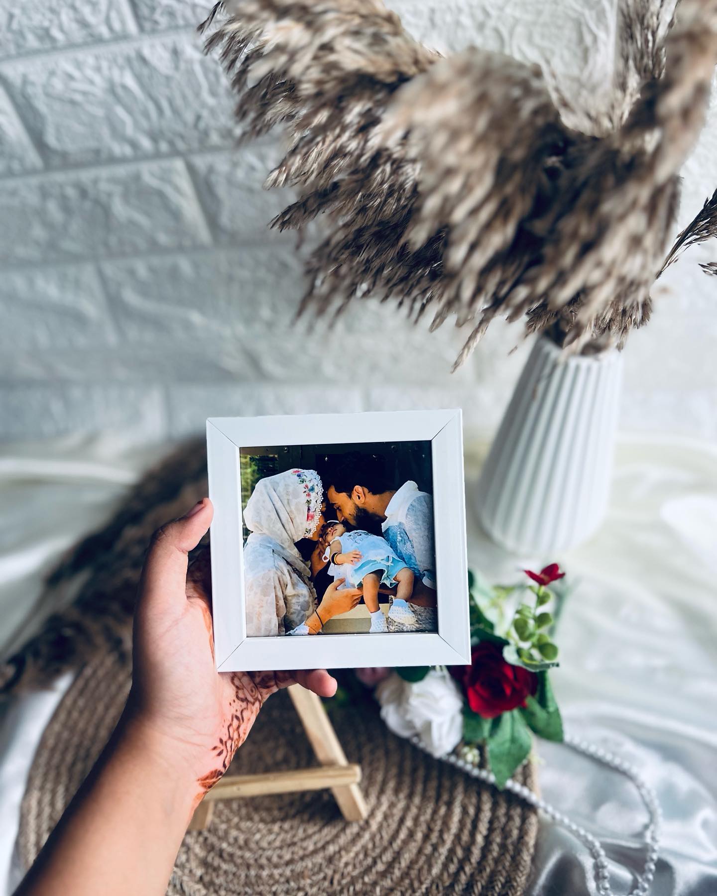 A compact white photo frame capturing a tender parents-and-baby moment, perfect for a shelf or desk.