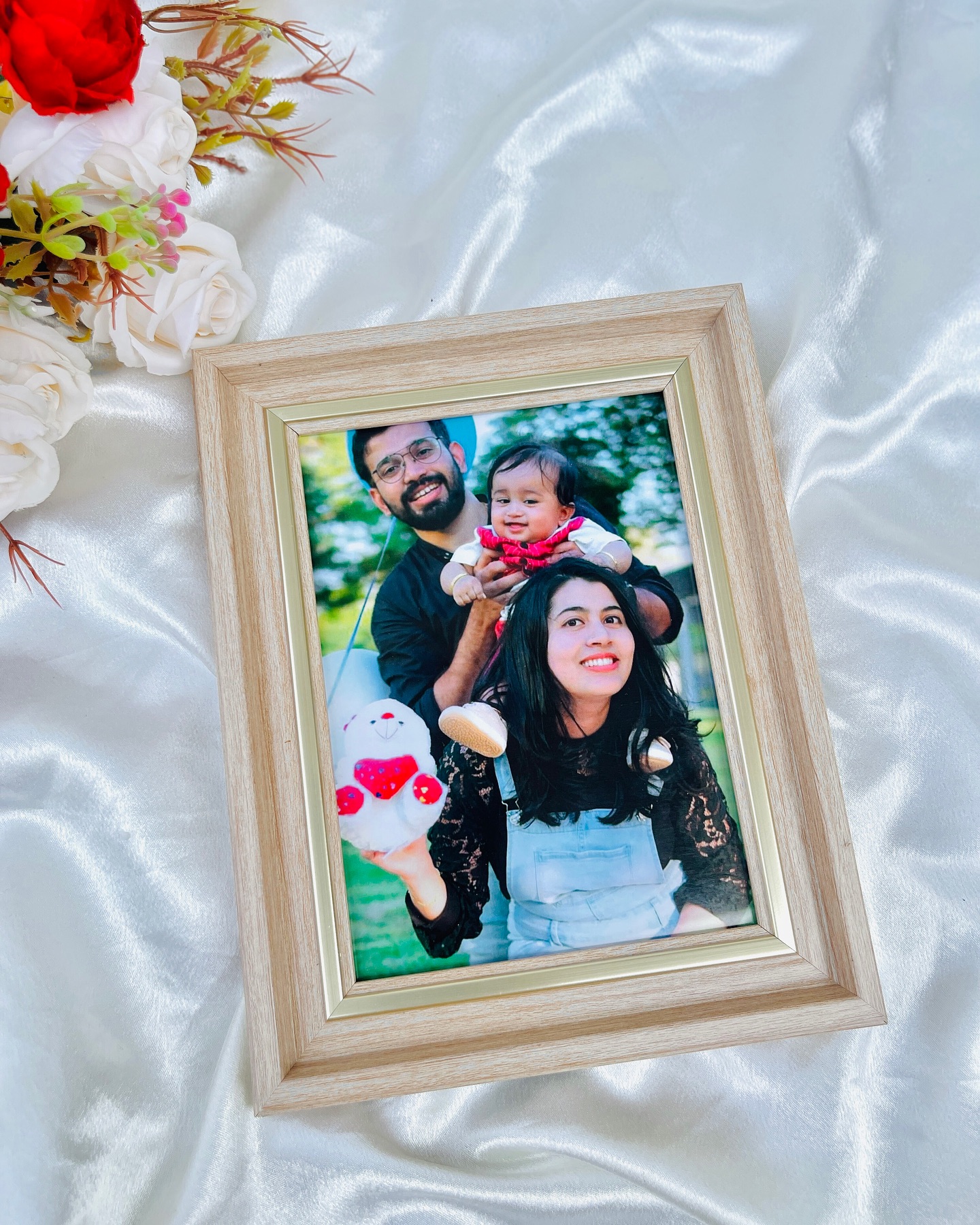 A light wood photo frame capturing a joyful family portrait, finished with a soft satin backdrop.