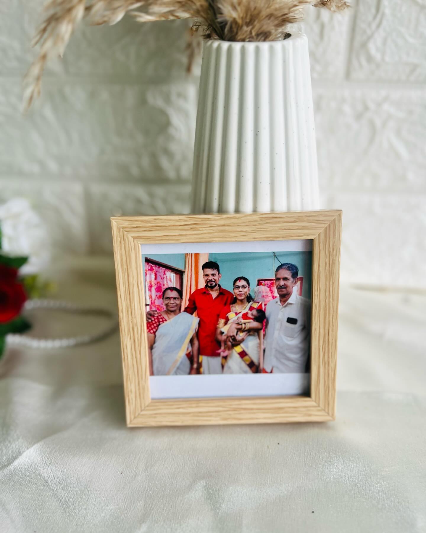A warm framed family photo paired with a ribbed ceramic vase and dried pampas grass for a heartfelt keepsake display.
