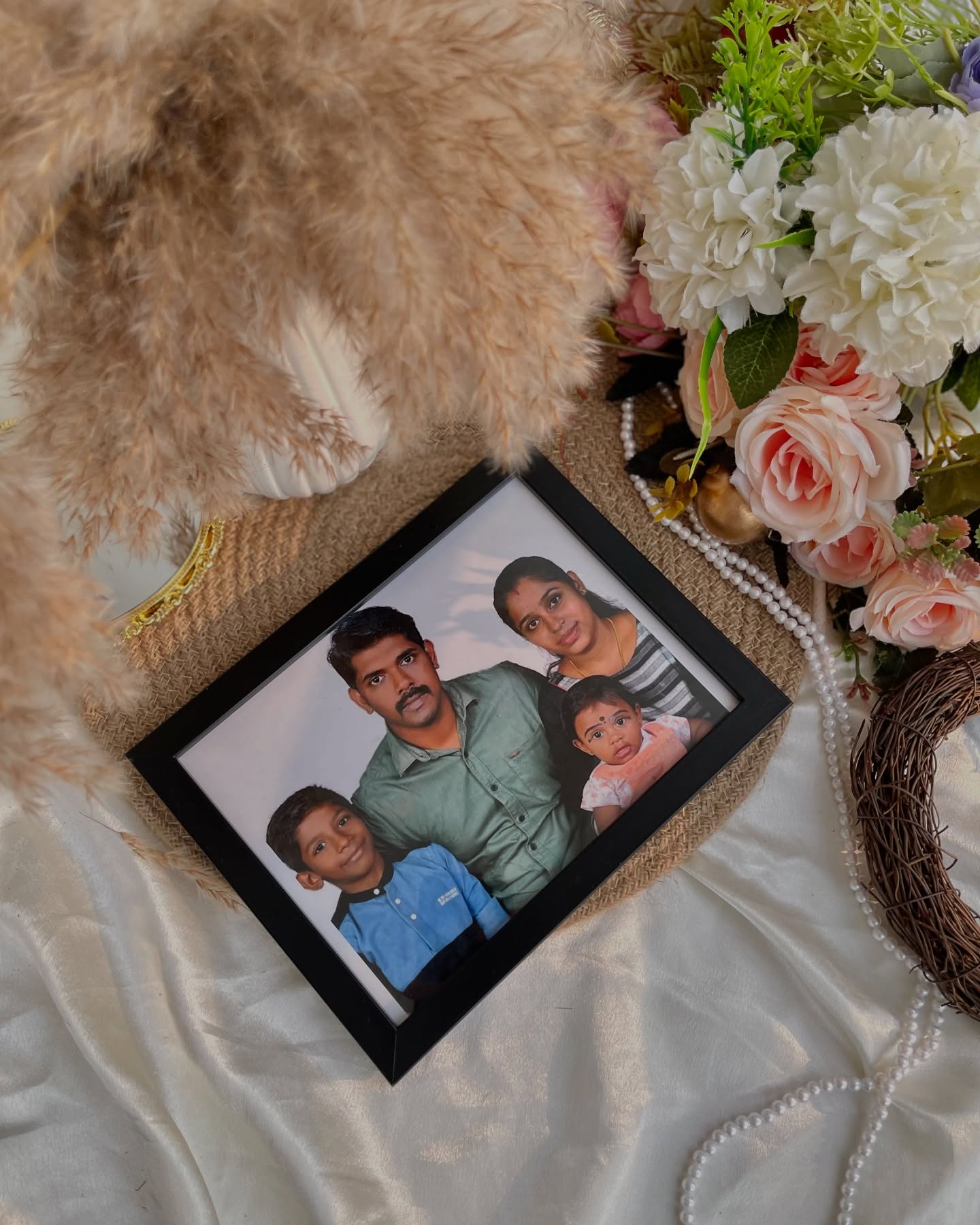 A framed family portrait styled with pampas grass, roses, and pearls for a timeless personalized keepsake.