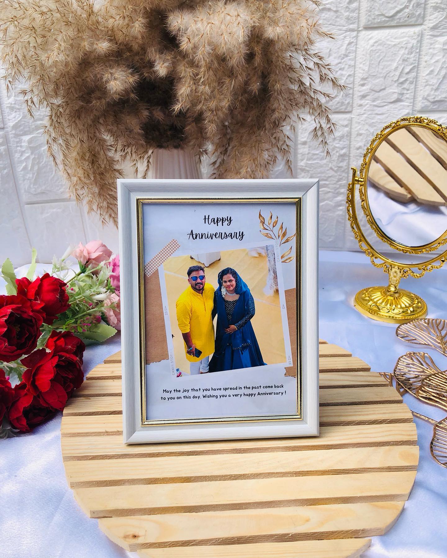 A softly styled photo frame with a couple's picture, a heartfelt anniversary message and a floral accent.