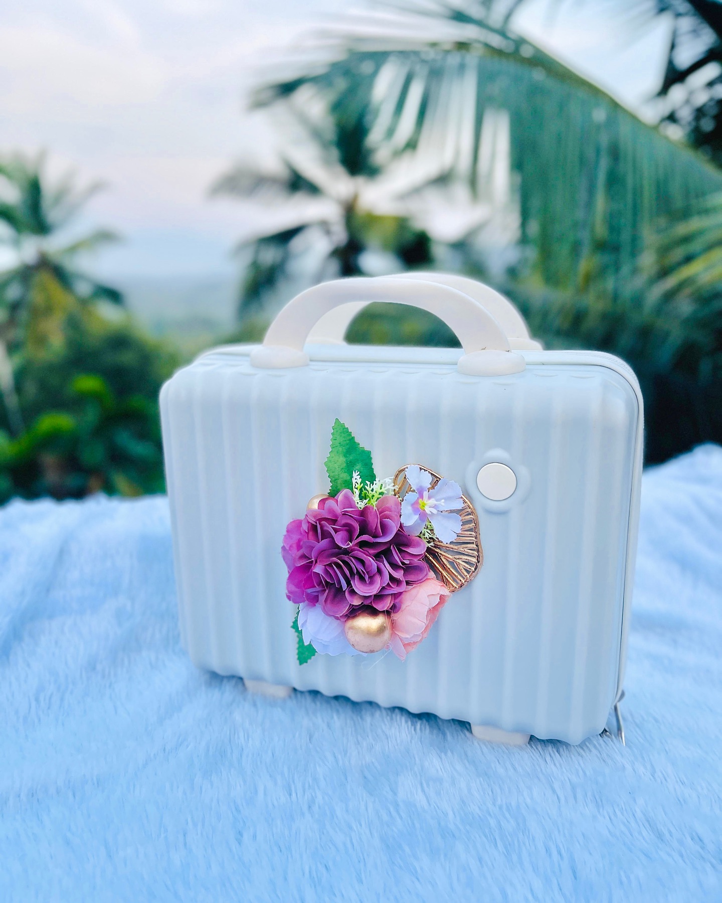 A pastel mini suitcase-style box decorated with a purple and pink floral bouquet accent.