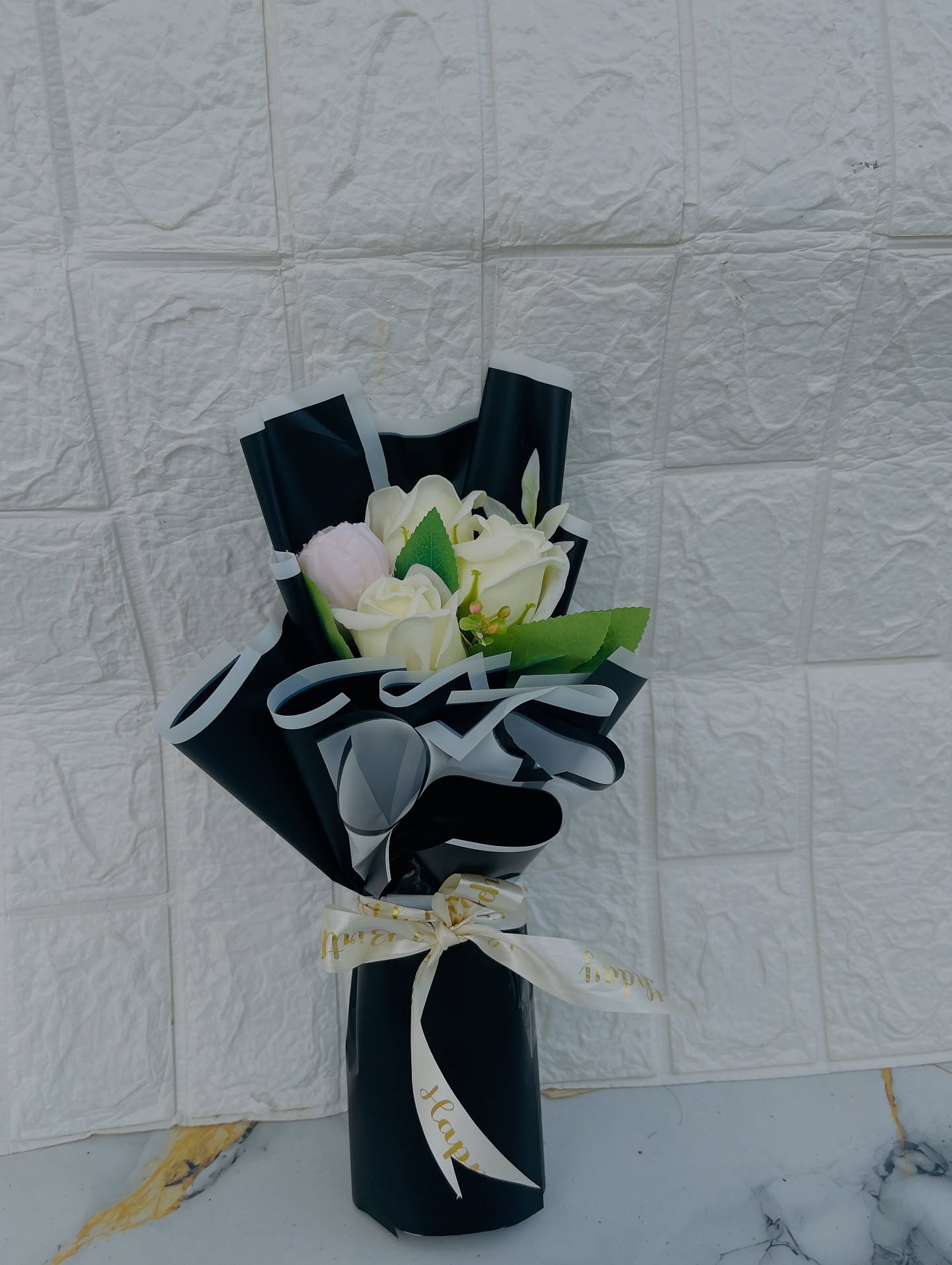 An elegant lilac gift box with a gold Happy Anniversary script and a dusty rose floral accent, tied with a satin bow.
