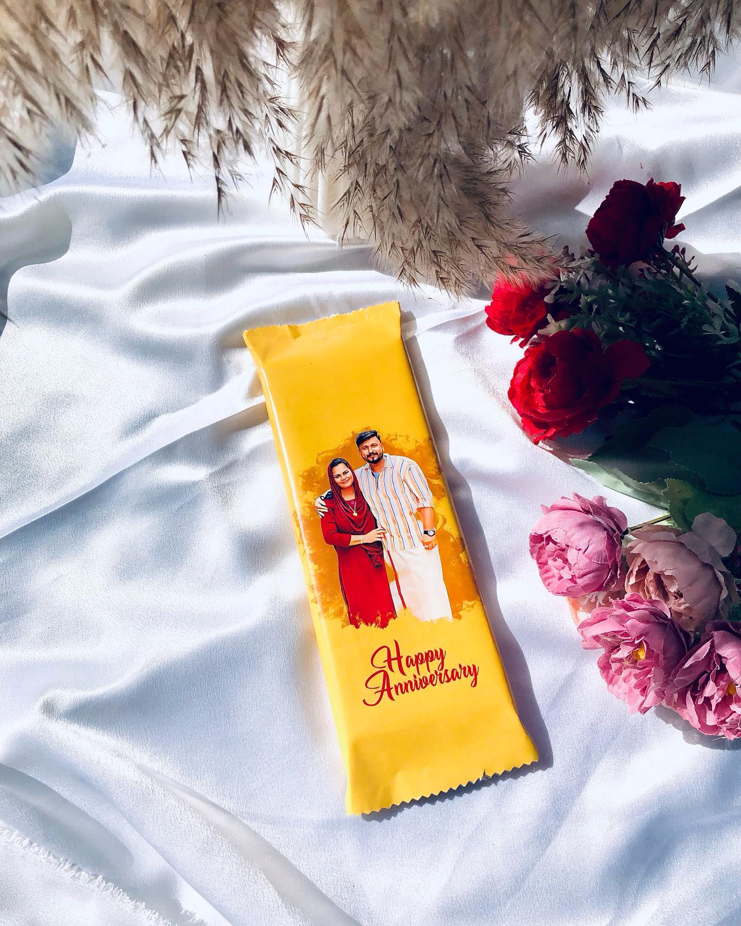A single chocolate bar wrapped with a personalized couple photo and 'Happy Anniversary' message.