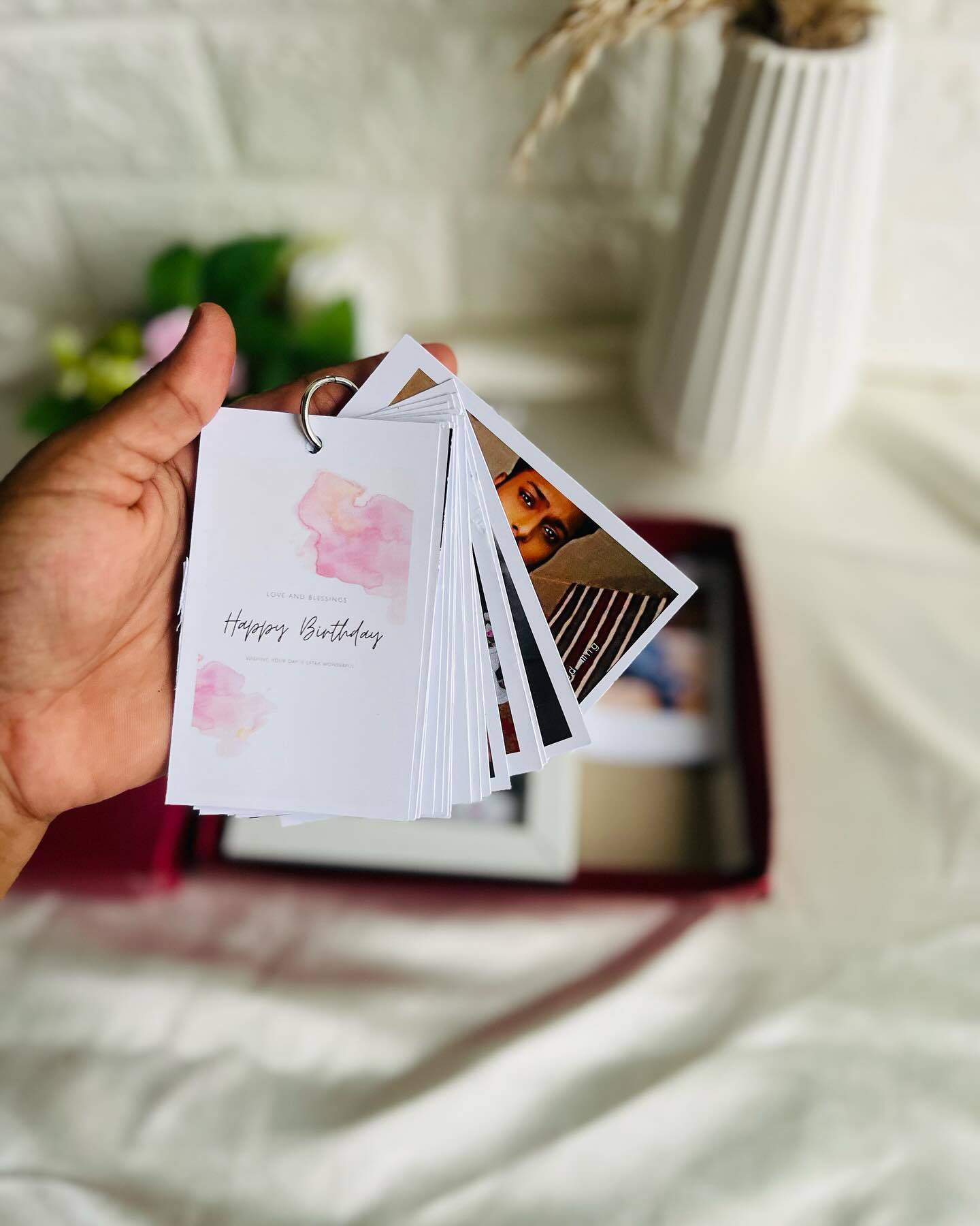 A ring-bound flip book of personal photos topped with a soft pink "Happy Birthday" cover card.