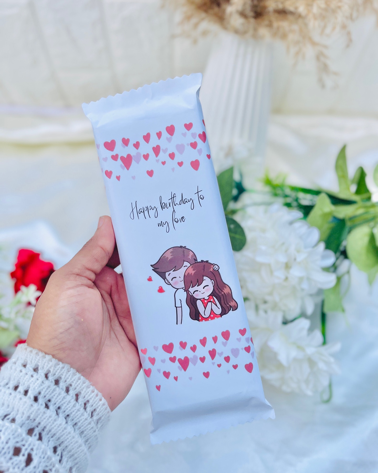 A custom-wrapped chocolate bar printed with a sweet cartoon couple and a 'Happy Birthday to my love' message.