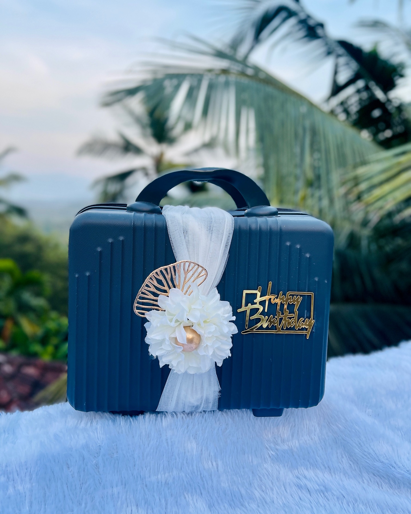A navy mini travel case dressed up with white florals, a gold leaf accent, and a Happy Birthday topper.