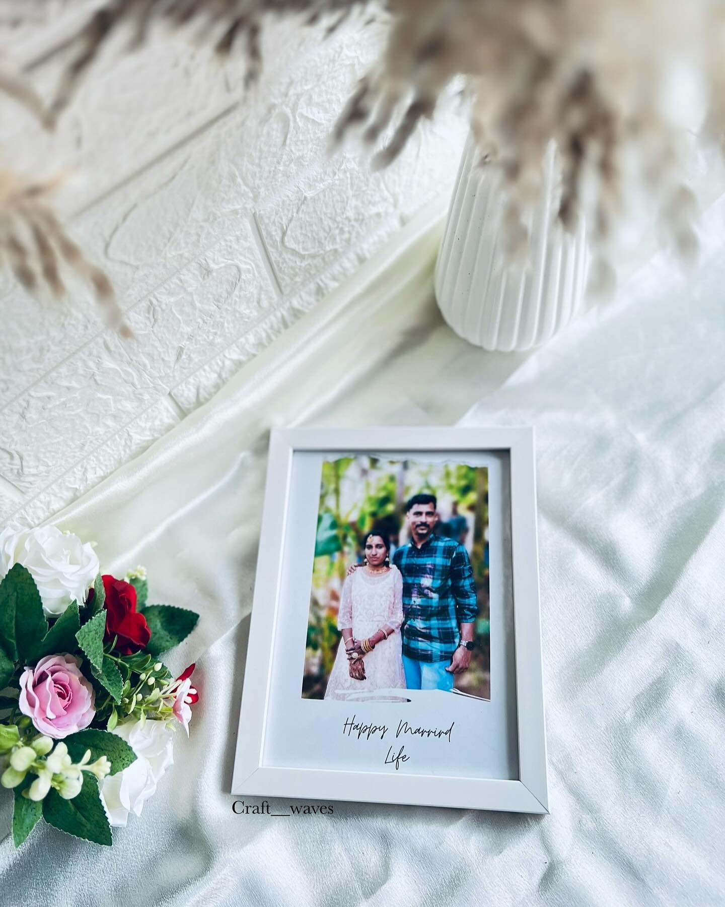 A simple white photo frame personalized with a couple's picture and a handwritten Happy Married Life message.