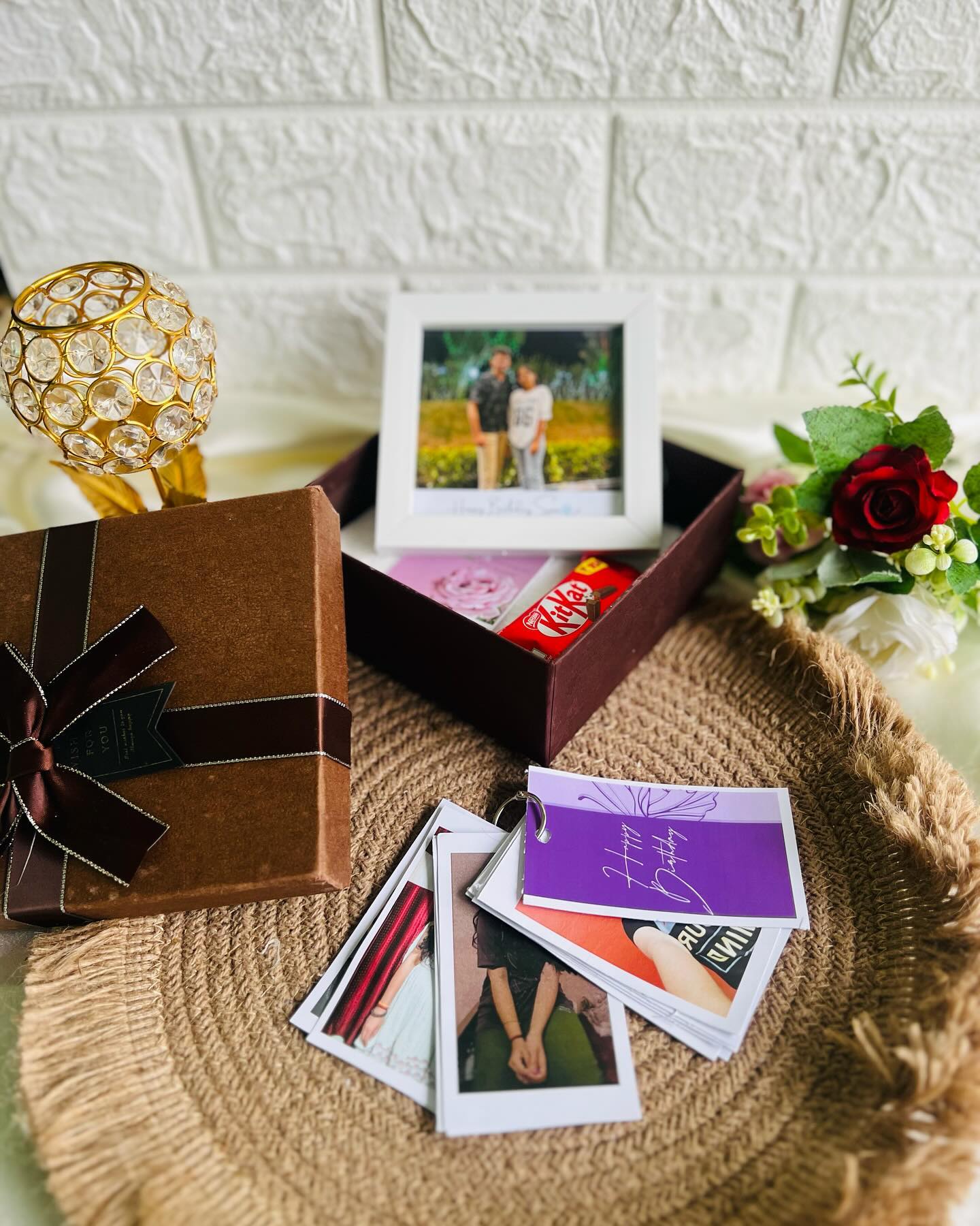 A stack of personalized instant-style photo prints paired with a ribboned gift box.