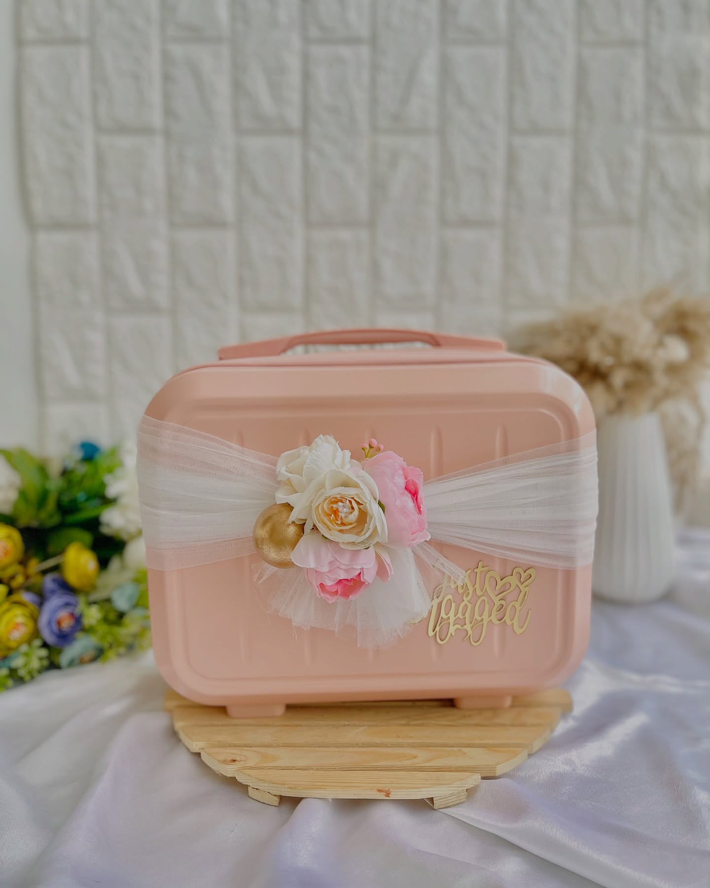 A blush vanity case wrapped in tulle and roses with a gold "Just Engaged" script.