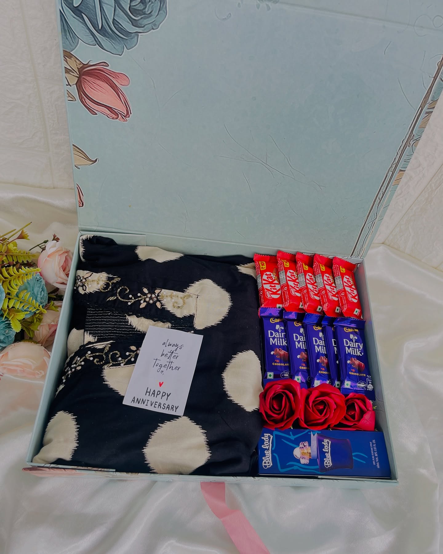 A printed kaftan paired with KitKat, Dairy Milk, silk roses, perfume, and a heartfelt anniversary note.