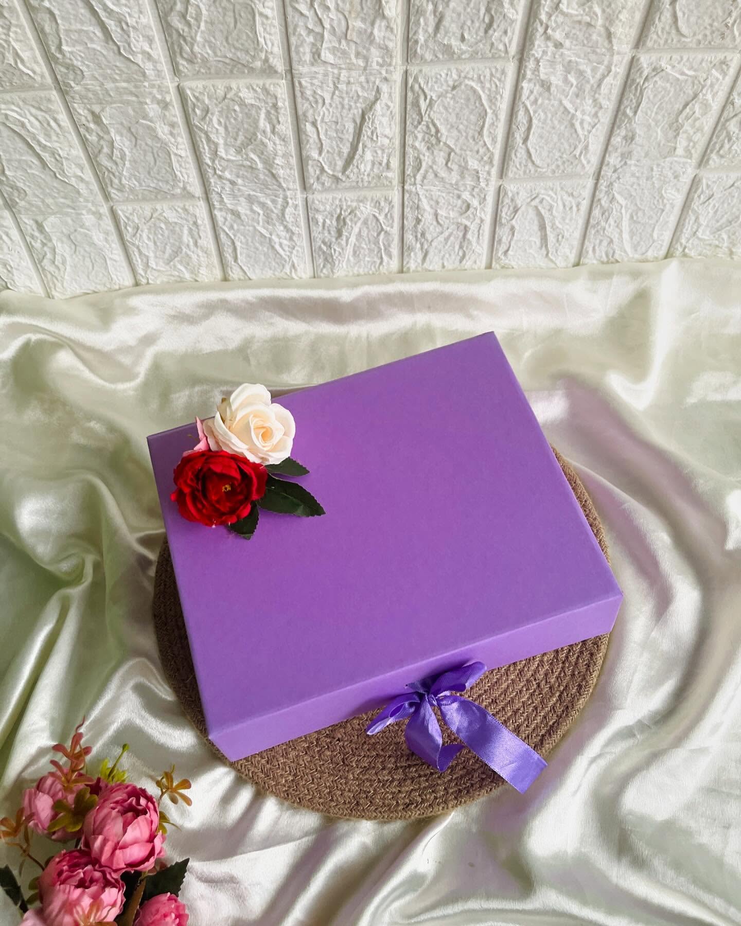 A sleek lavender gift box adorned with a red and ivory rose, finished with a matching satin ribbon.