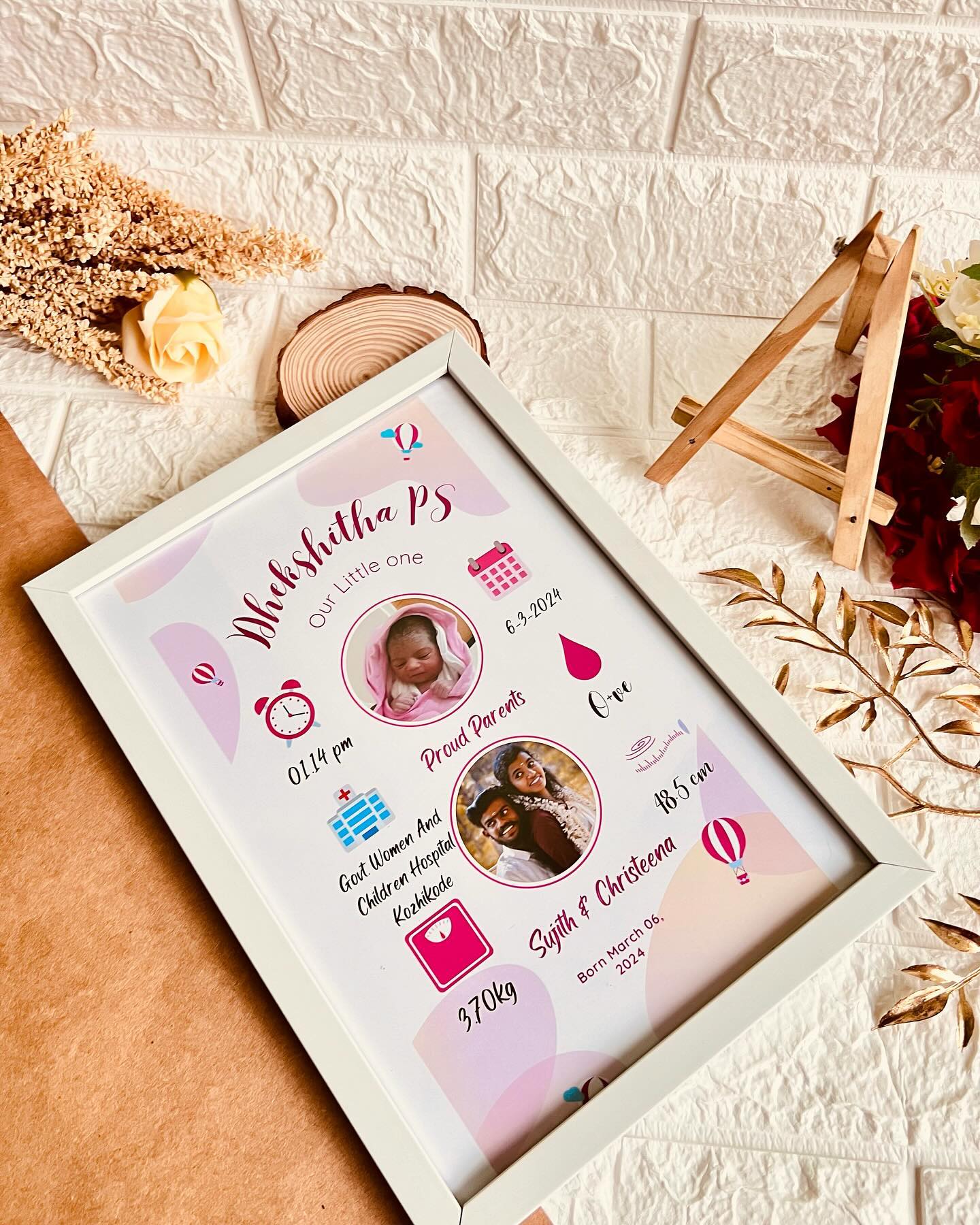 A personalised birth-details poster in a soft white frame, complete with baby and parent photos.