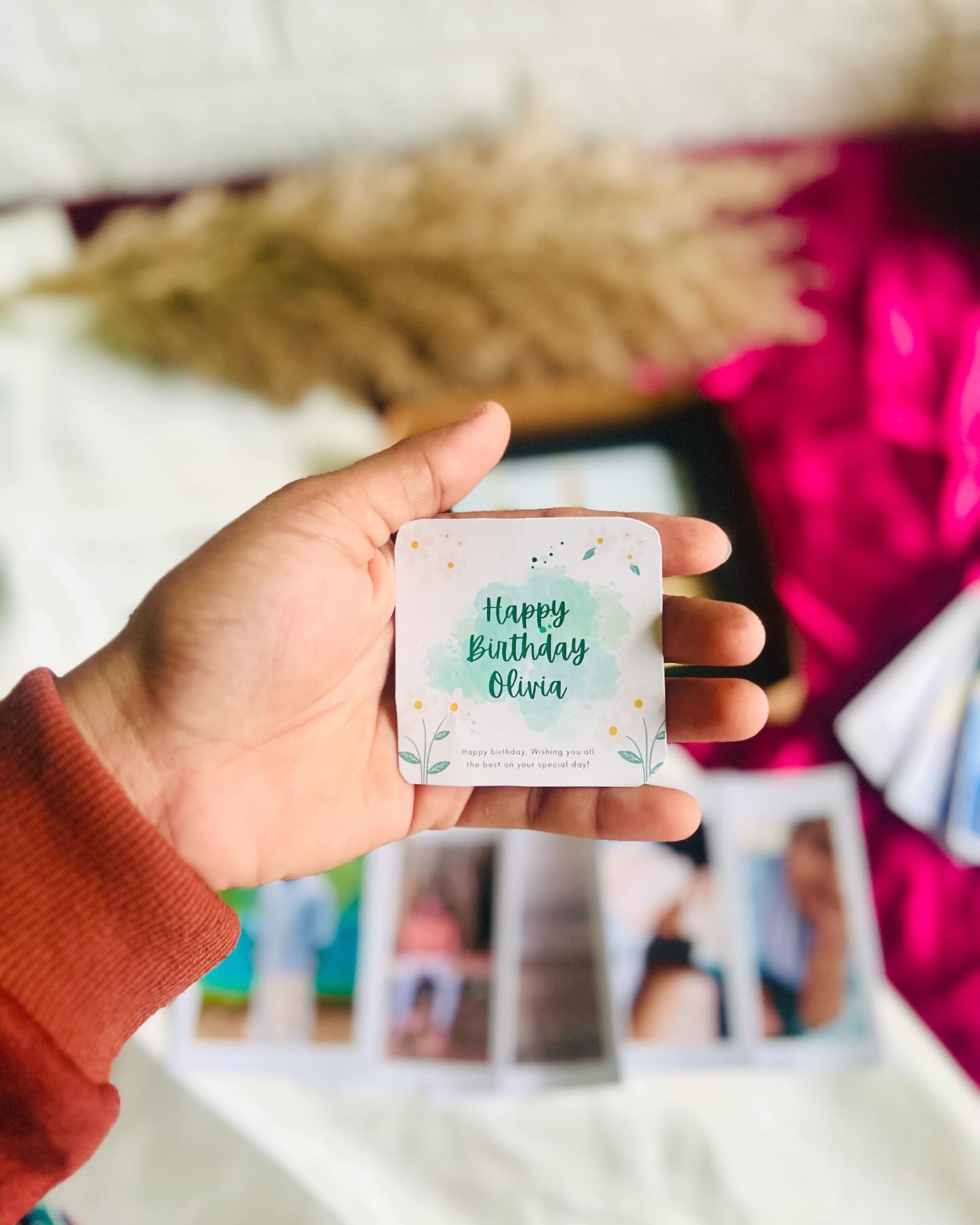 A personalized birthday flat-lay set with a framed couple photo, instant-style photo prints, a mini photo album, and chocolate.