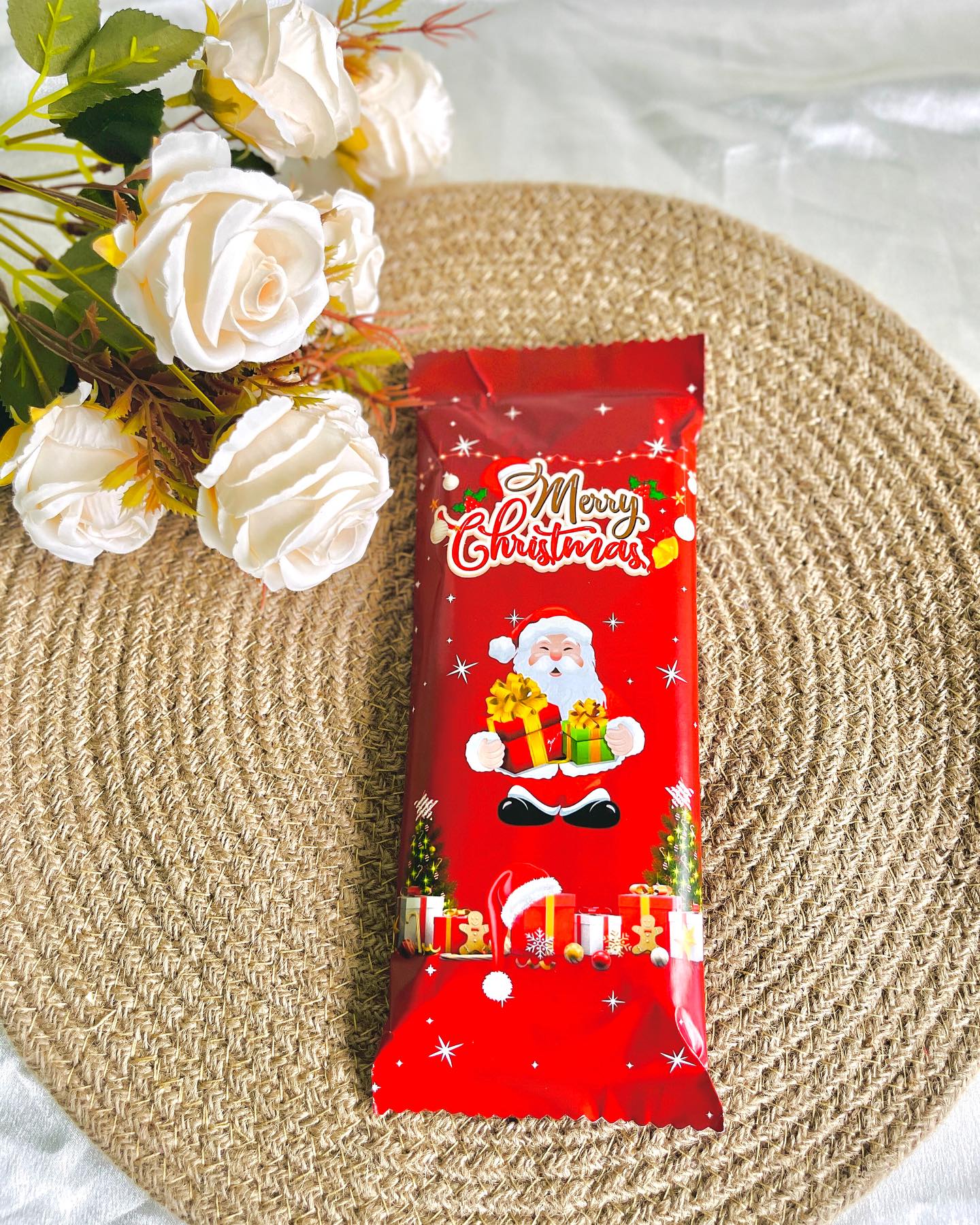 A festive foil-wrapped chocolate bar decorated with Santa and holiday gifts, ready to gift or add to a hamper.