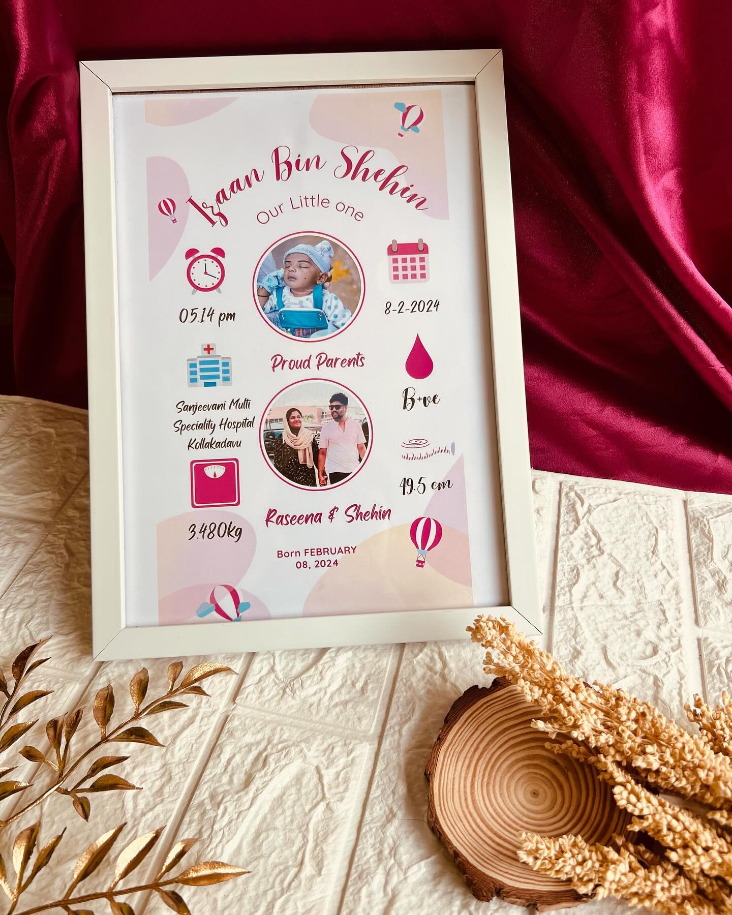 A pink personalized birth announcement frame for baby Izaan, with parent and baby photos and birth stats.