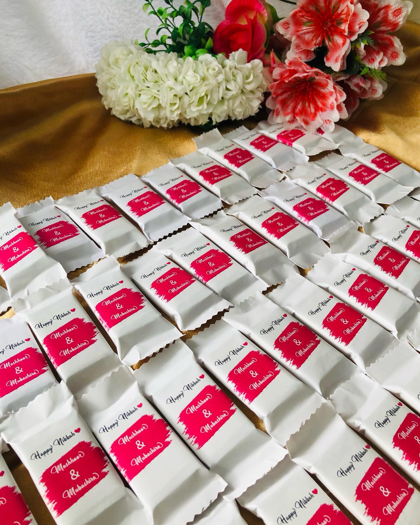 A tray of personalized wedding chocolate favors wrapped with the couple's names for guests to take home.