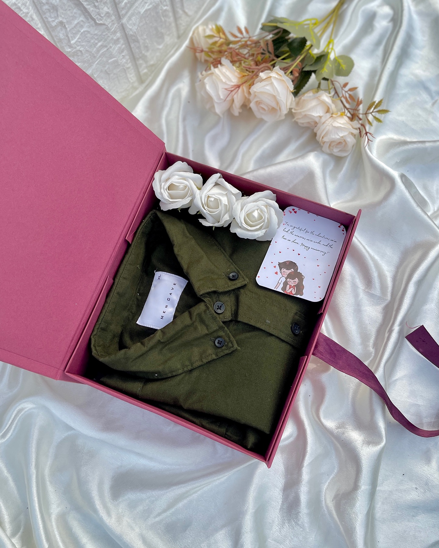 An olive green shirt gift-boxed with white roses and a sweet anniversary greeting card.