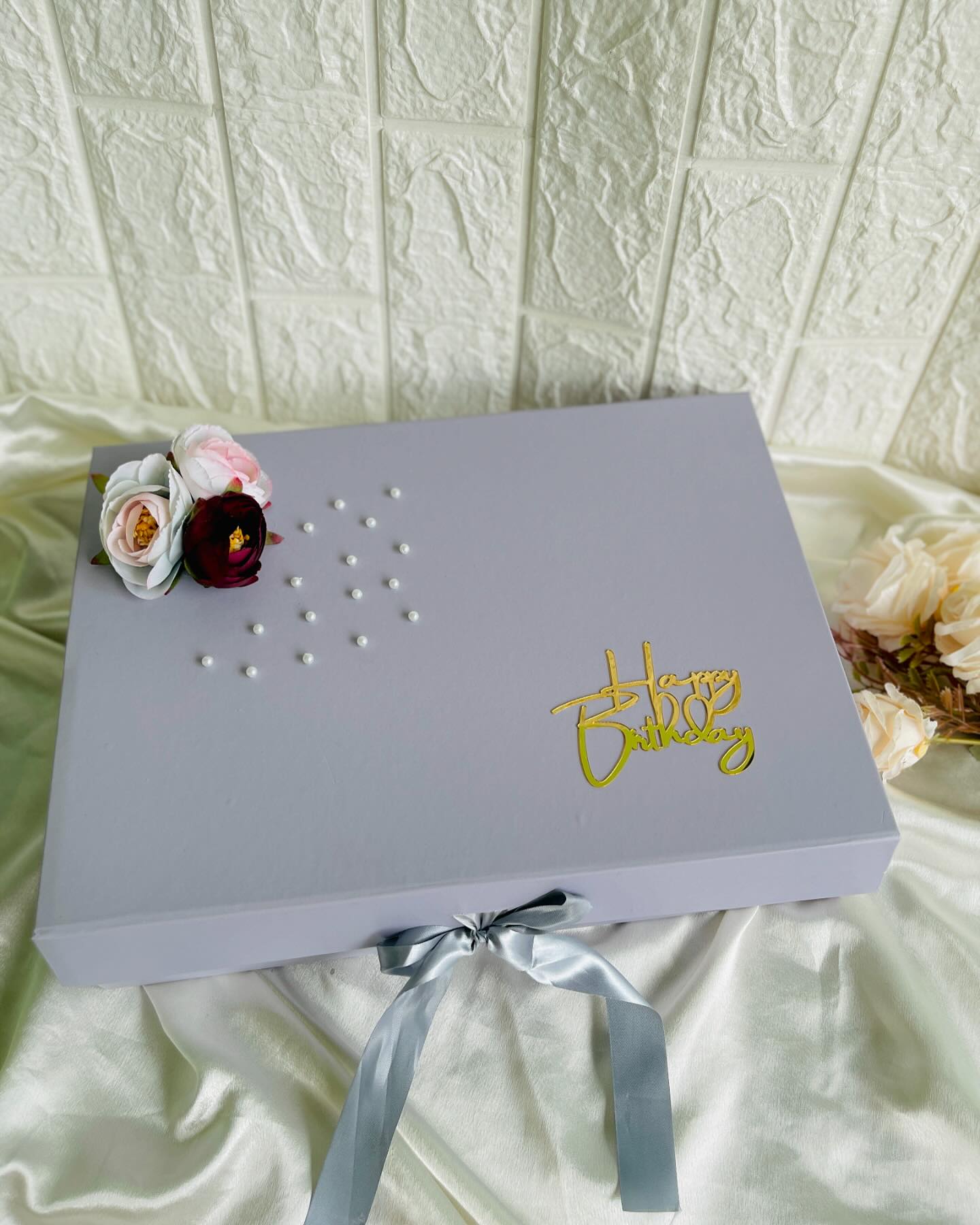 An elegant lavender gift box finished with pearl detailing, silk florals and a gold-script Happy Birthday topper.