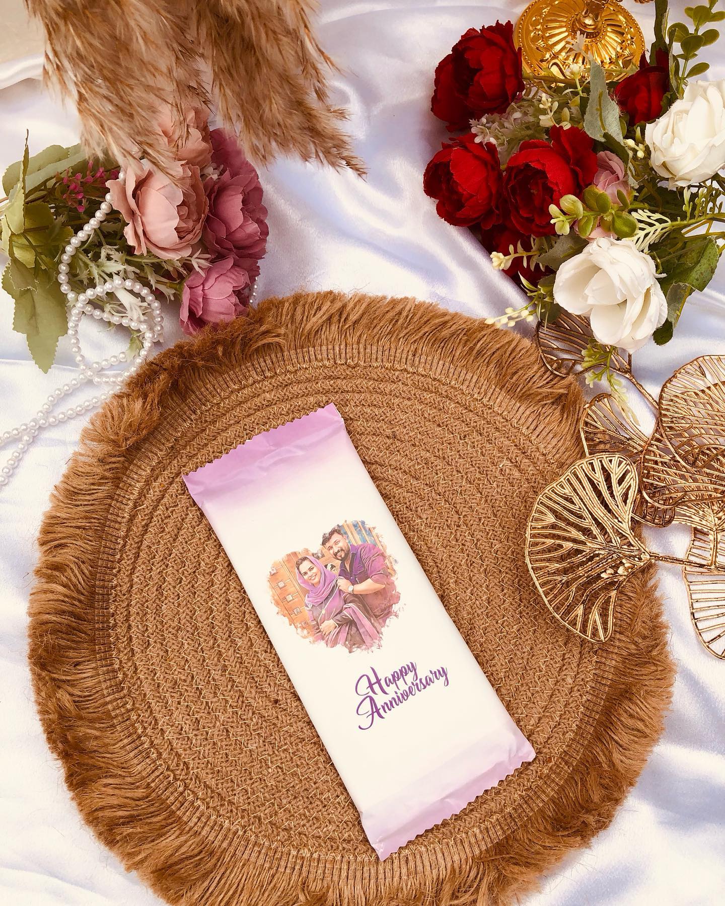 A pastel-wrapped chocolate bar printed with a couple's photo and a Happy Anniversary message.
