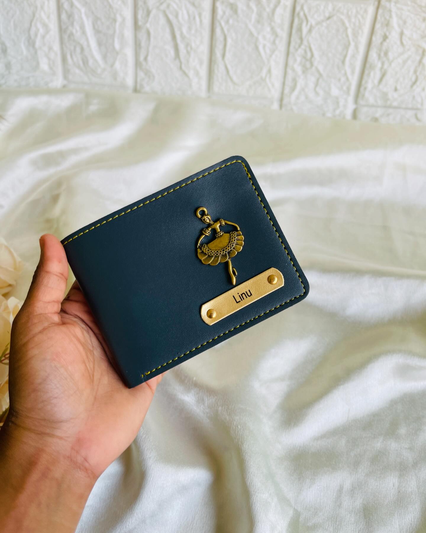 A navy leather wallet with a gold ballerina charm and a custom name plate, ready to gift.