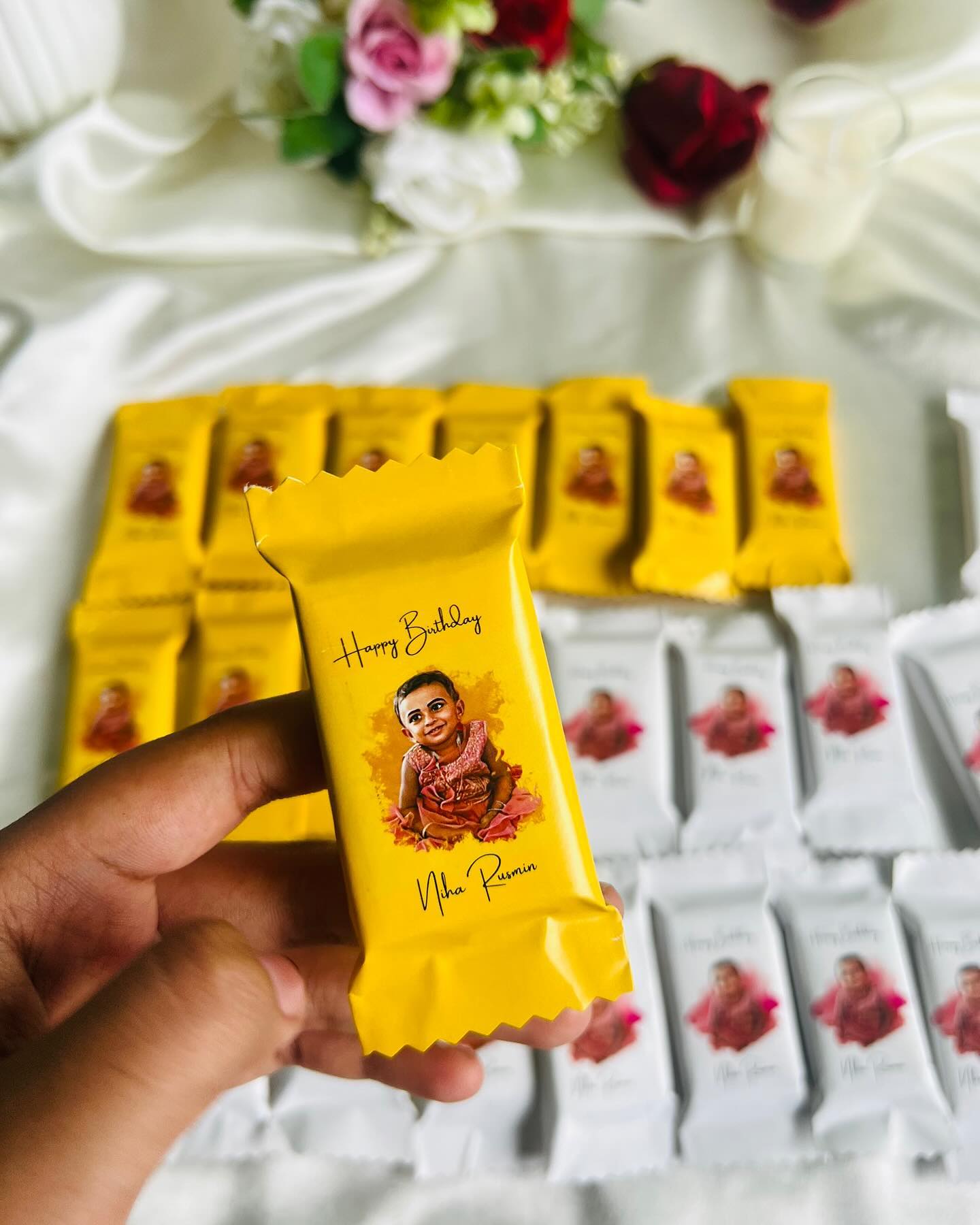 A stack of custom-wrapped chocolate bars featuring the birthday child's illustrated portrait and name.