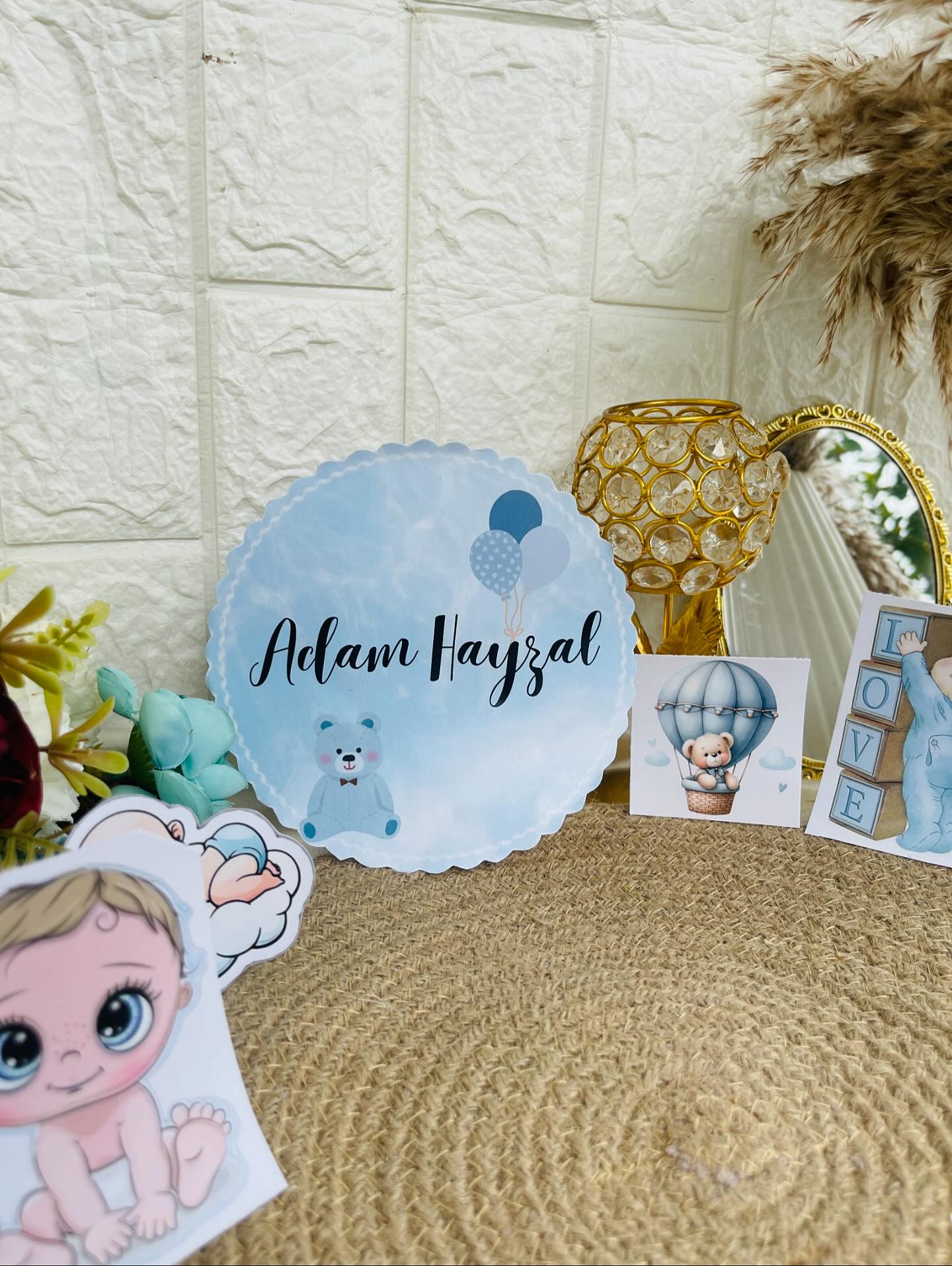 A custom name and date plaque paired with baby-themed cutout props, perfect for a first birthday celebration.