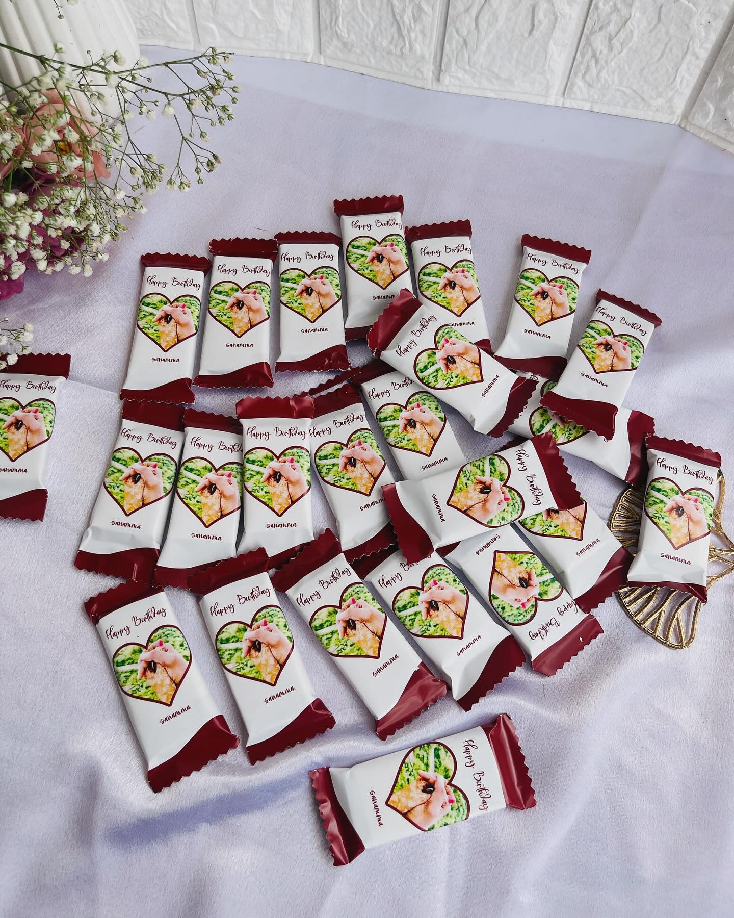 A large bunch of chocolate bars wrapped in maroon photo sleeves with a heart-framed photo and a personal name.