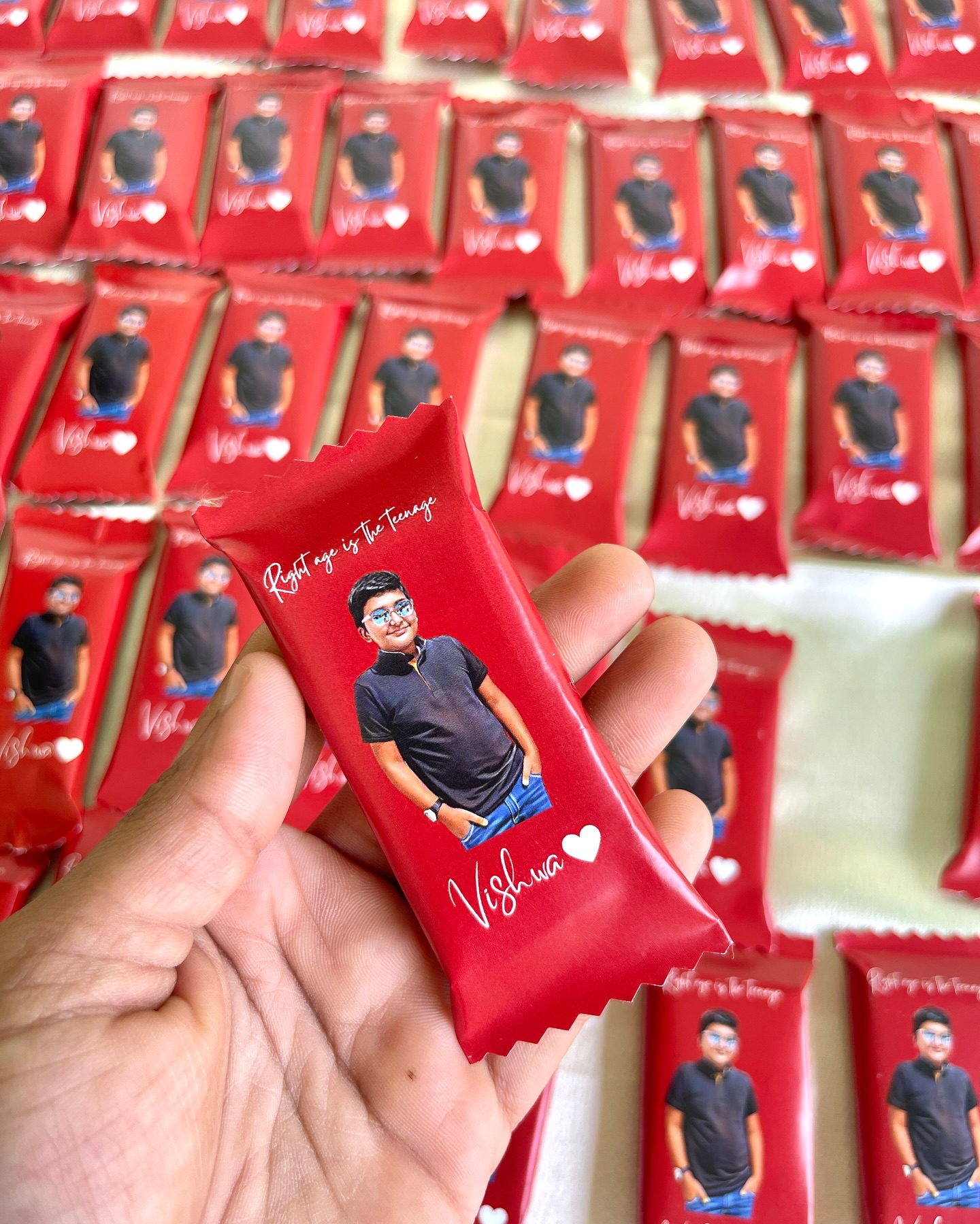A batch of custom-wrapped chocolate bars featuring a photo, name, and message, perfect as teen birthday favors.