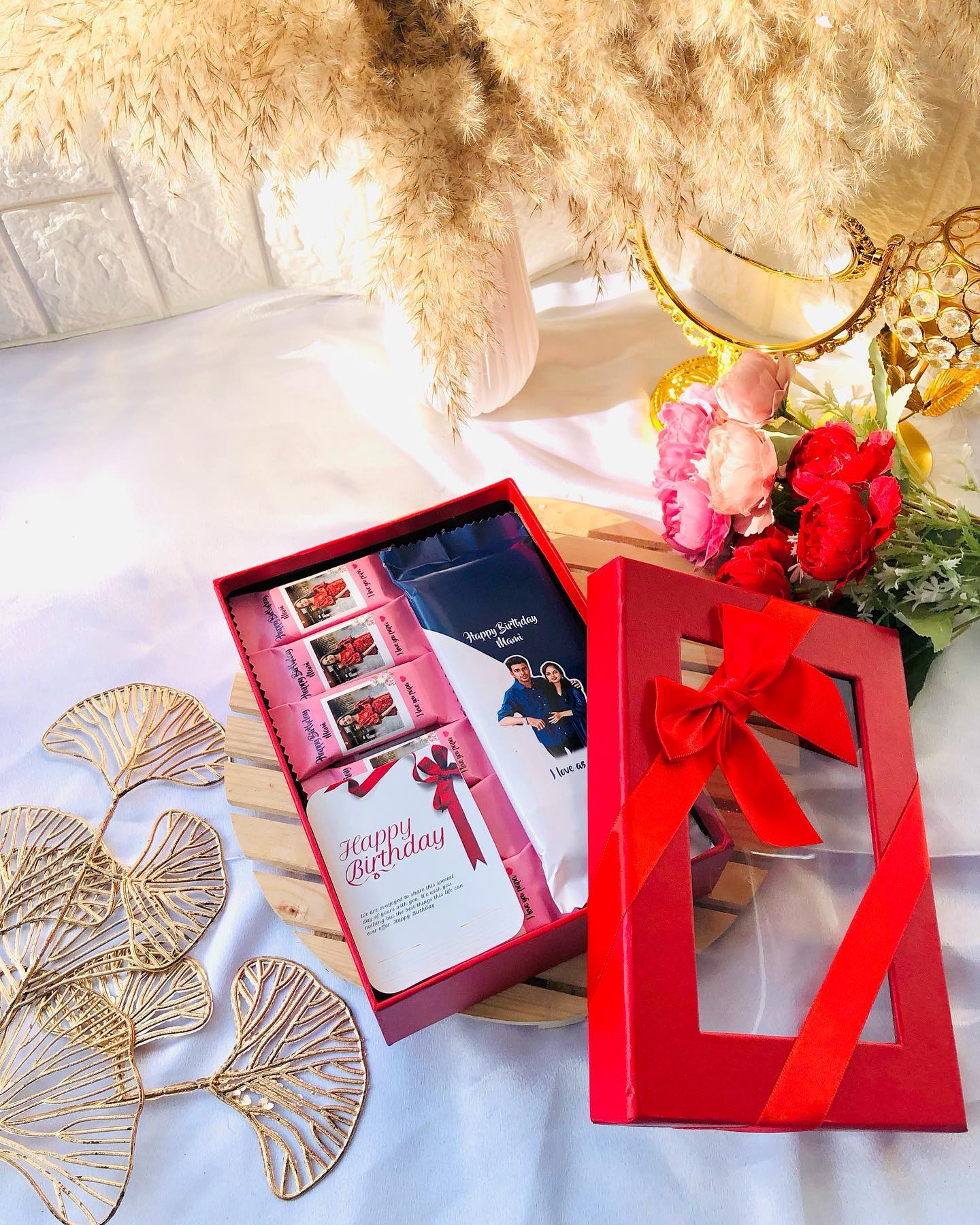 A red gift box filled with photo-personalized chocolate bars, a birthday card, and a large custom photo chocolate slab.