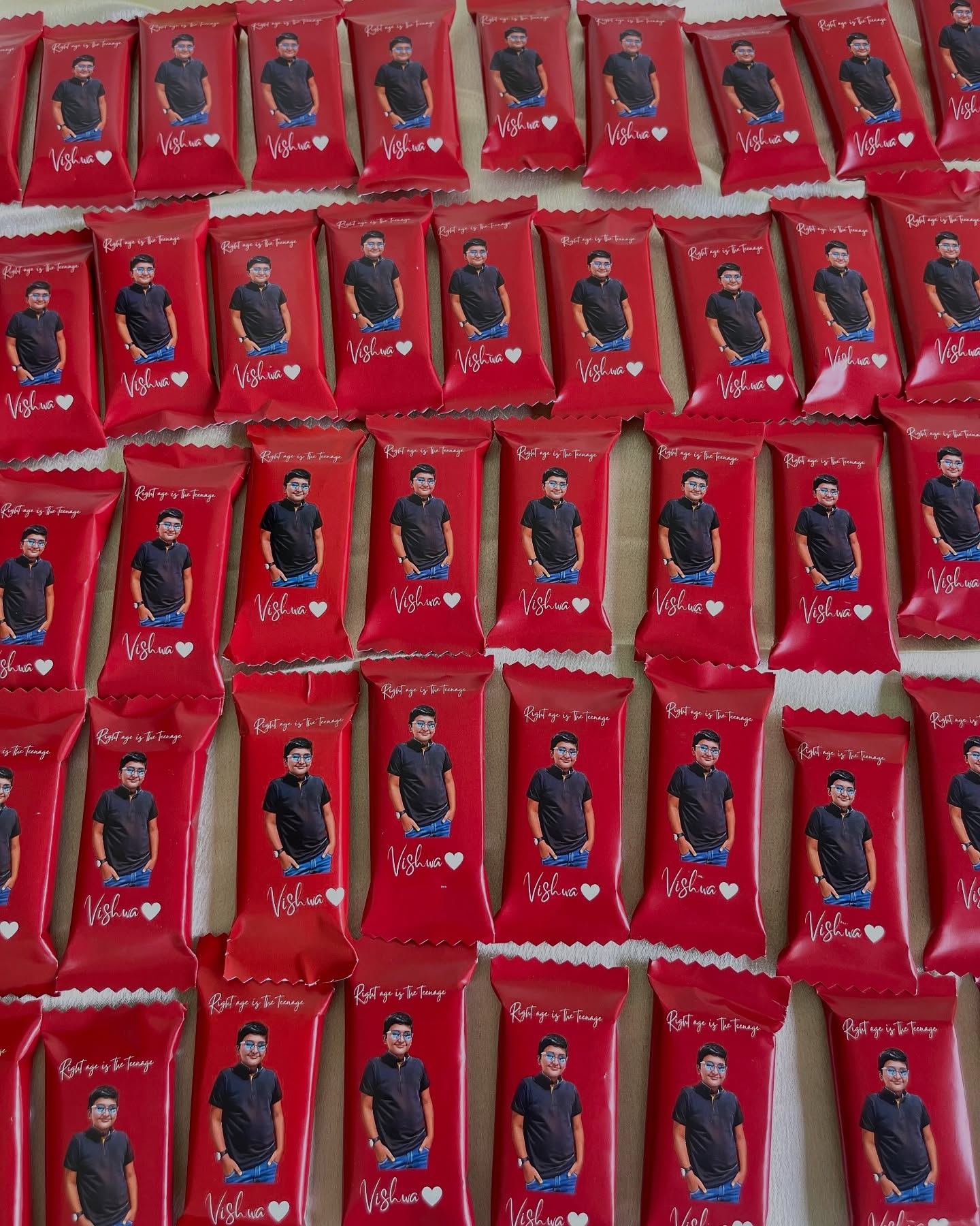 Rows of custom-wrapped chocolates printed with a birthday photo and name, perfect as party favors.