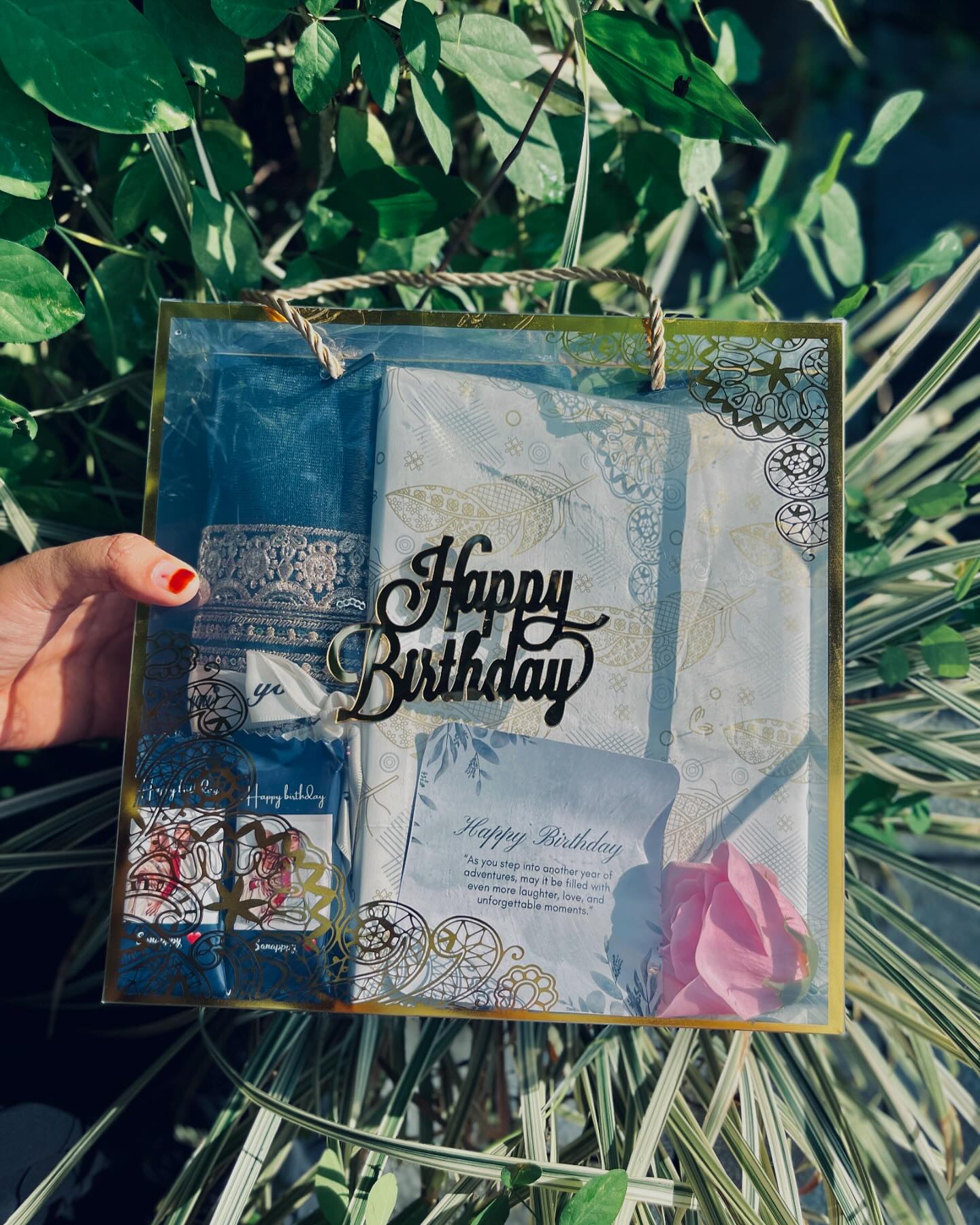 A keepsake black gift box holding a framed photo, stacks of polaroids, and matching greeting tags.